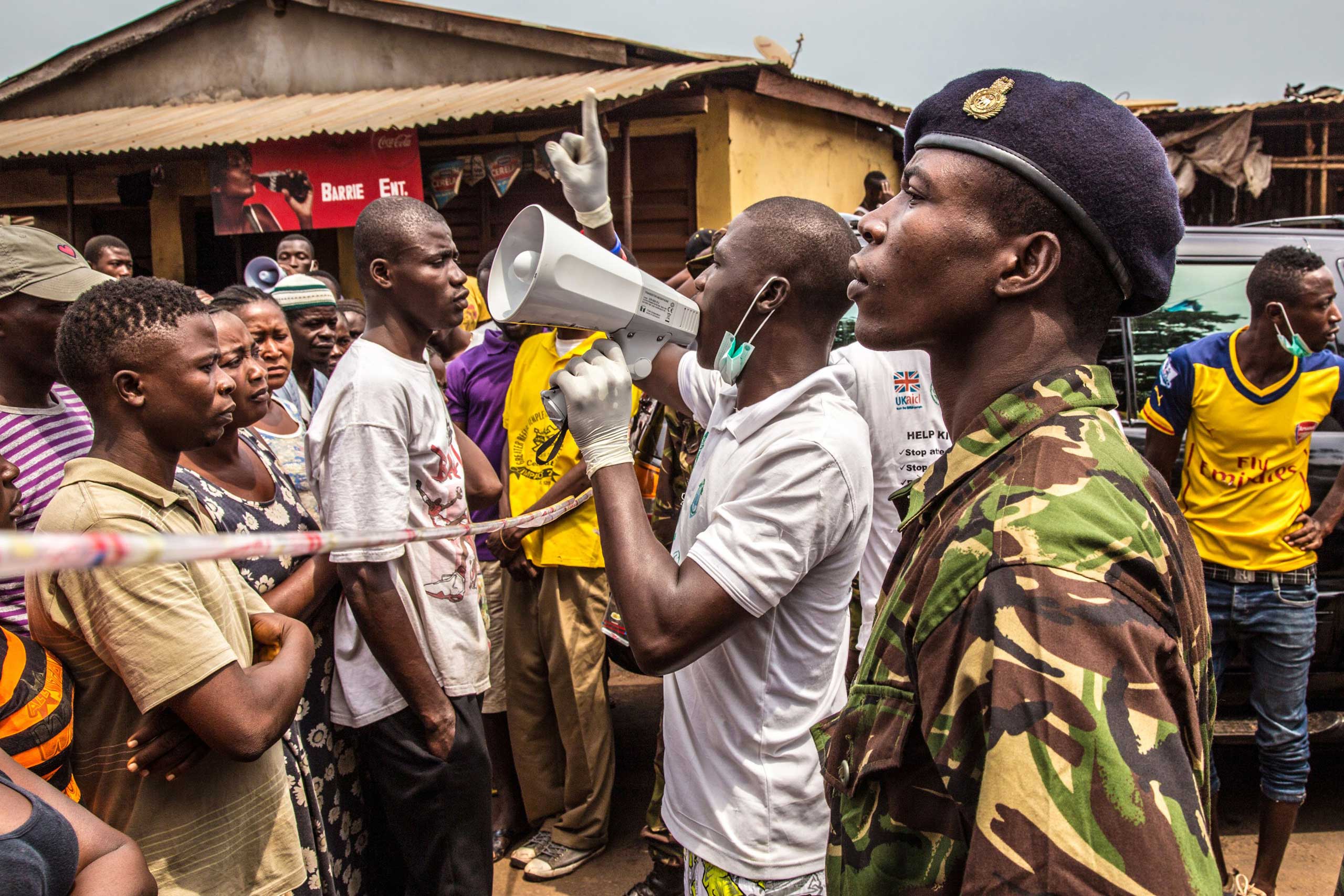 People stand in line for food to be distributed to them as a health worker makes an announcement in Freetown, Sierra Leone on March 27, 2015. (Michael Duff—AP)