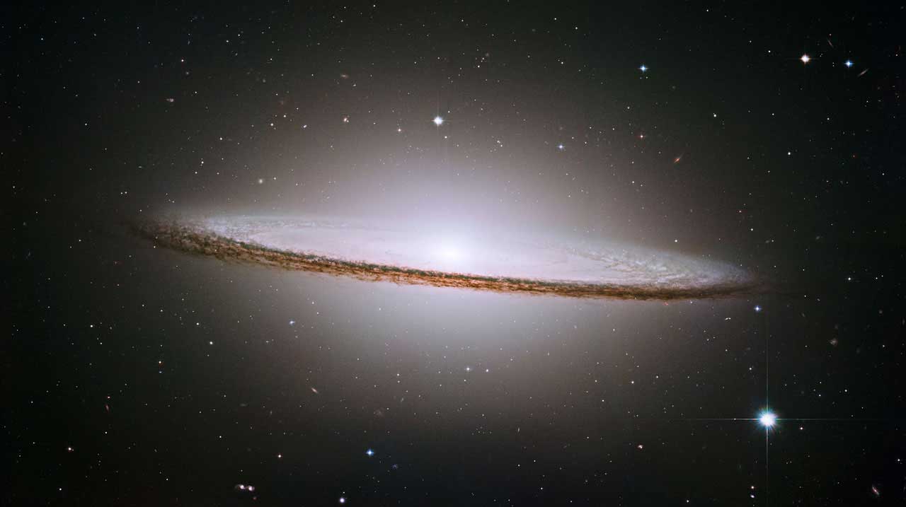 The Sombrero Galaxy:
                              
                              Also known as Messier 104 (M104), the galaxy's hallmark is a brilliant white, bulbous core encircled by the thick dust lanes comprising the spiral structure of the galaxy. The Sombrero lies at the southern edge of the rich Virgo cluster of galaxies and is one of the most massive objects in that group, equivalent to 800 billion suns. The galaxy is 50,000 light-years across and is located 28 million light-years from Earth.Image released on Oct. 2, 2004