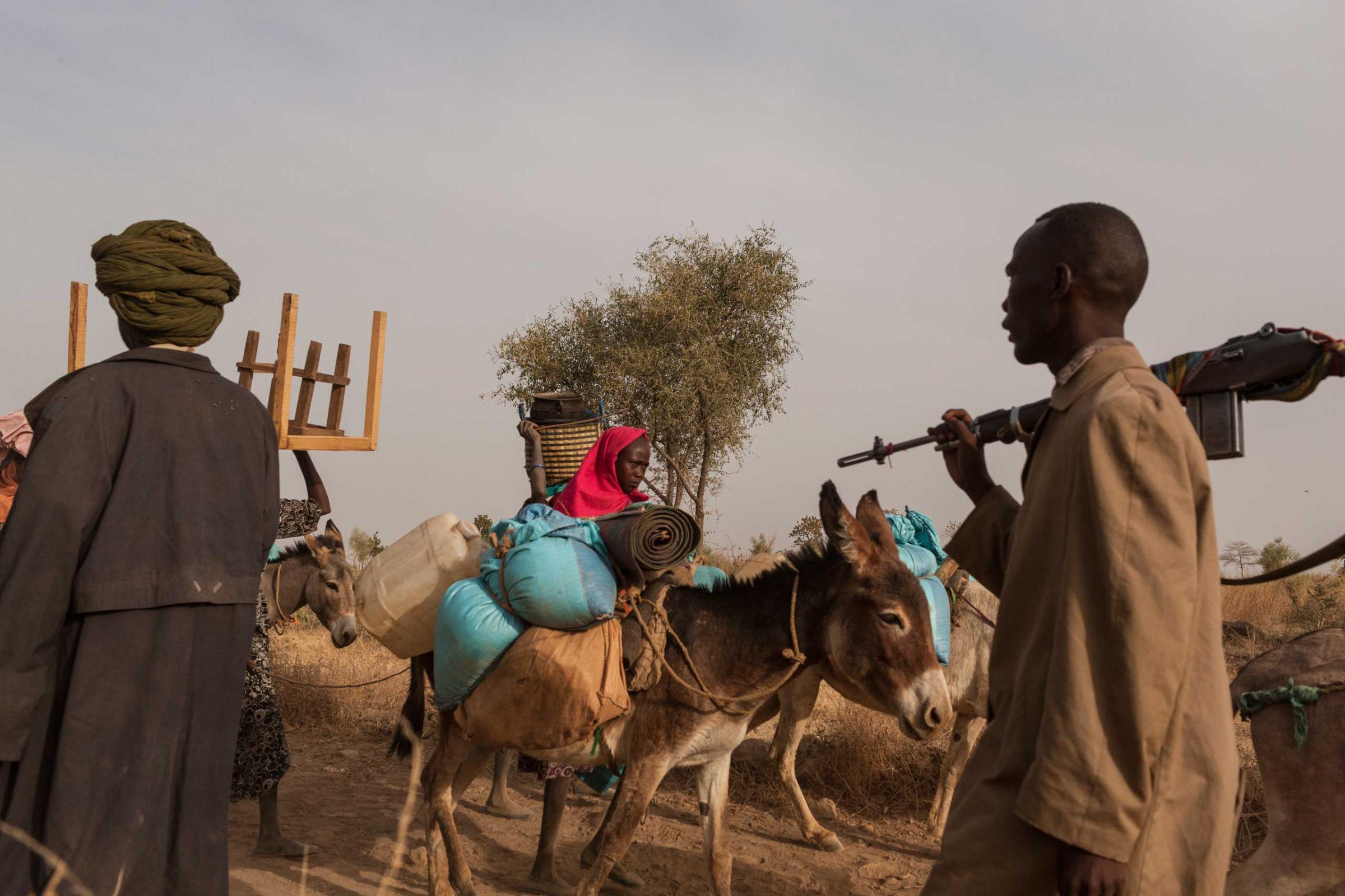 Civilians flee their homes with the few belongings they could carry, while members of the SLA-AW walk toward the front lines in Central Darfur, Sudan, on March 4, 2015.
