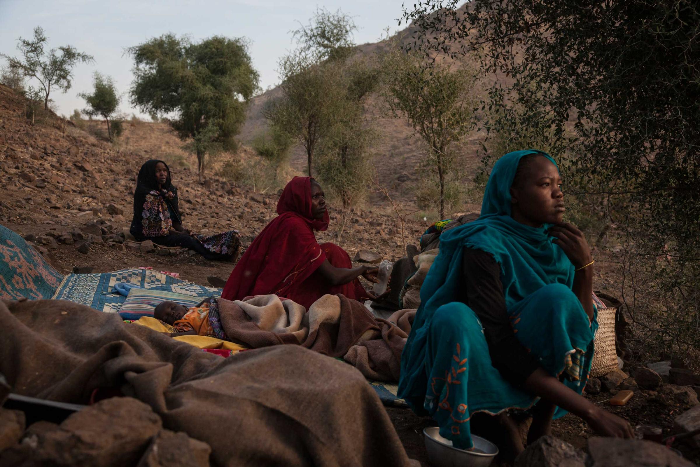 Women from the town of Golo wake up in the morning on the side of a mountain where they sleep outside of Kome in Central Darfur, Sudan, on Feb. 28, 2015.