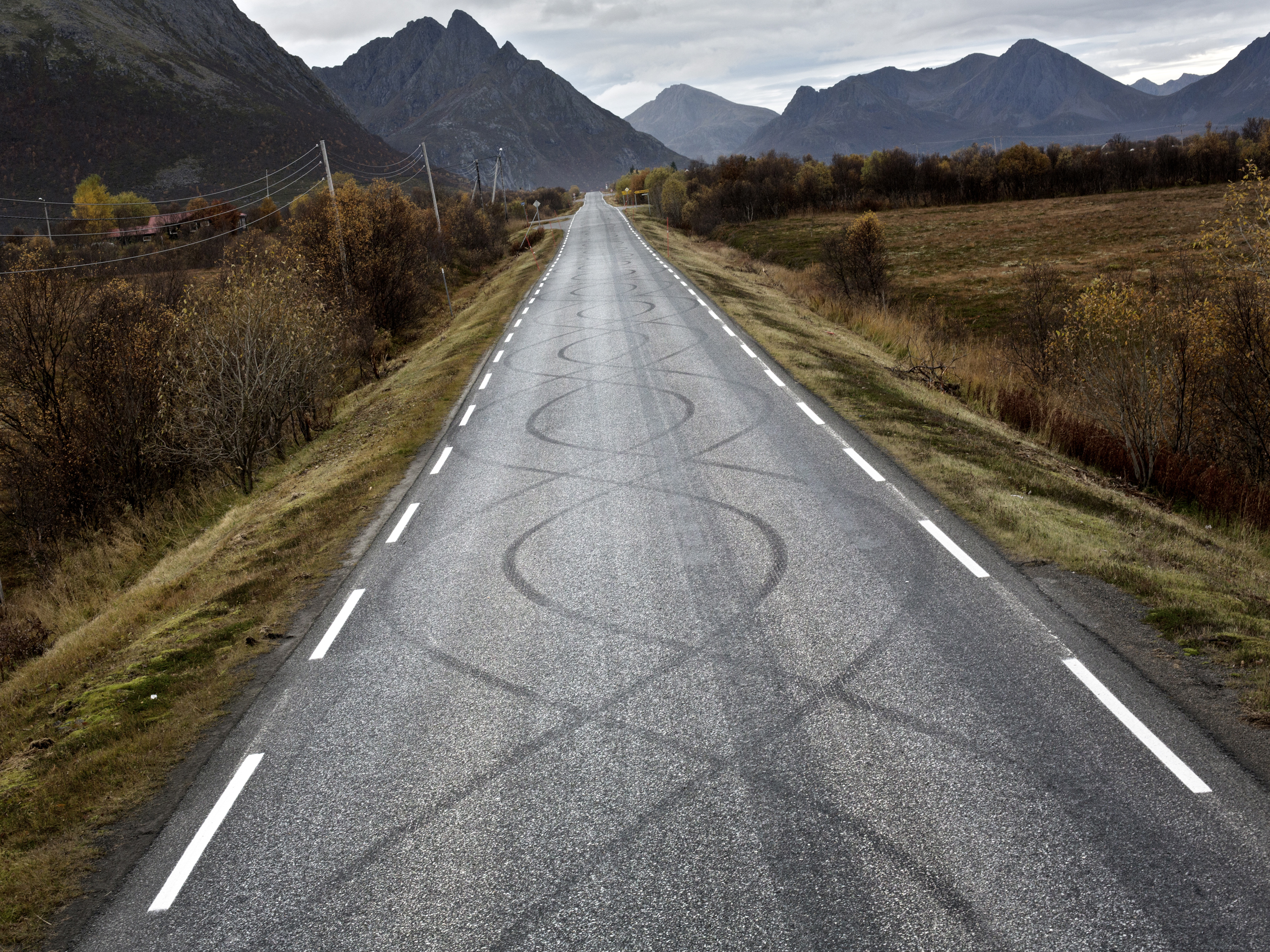 Rubber tire skidmarks form artistic figure-8s on the road out from Myre. Myre is home to many car enthusiasts. 2012, Vesterålen, Norway.