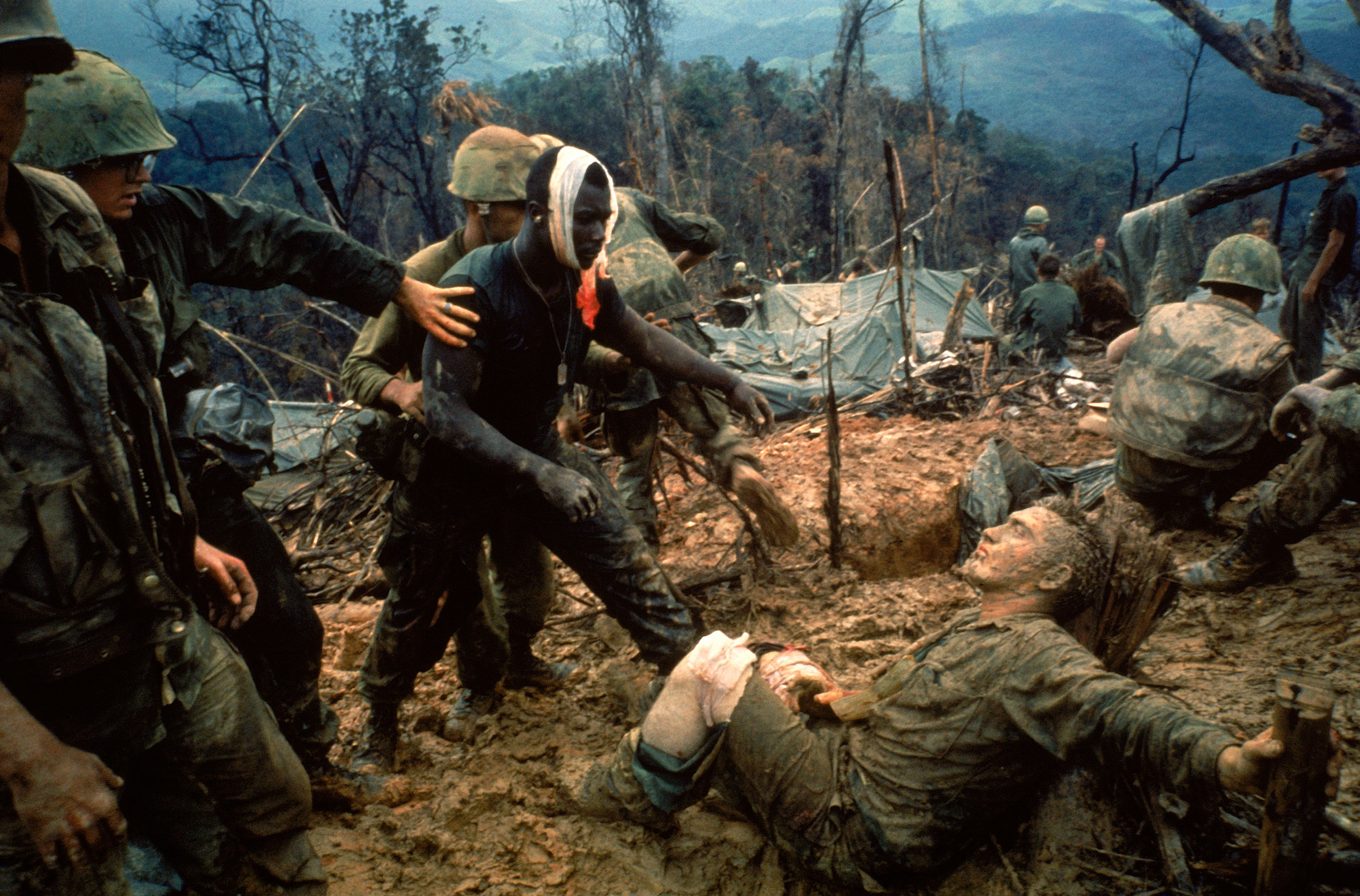Wounded Marine Gunnery Sgt. Jeremiah Purdie (center, with bandaged head) reaches toward a stricken comrade after a fierce firefight south of the DMZ in Vietnam in Oct. 1966.