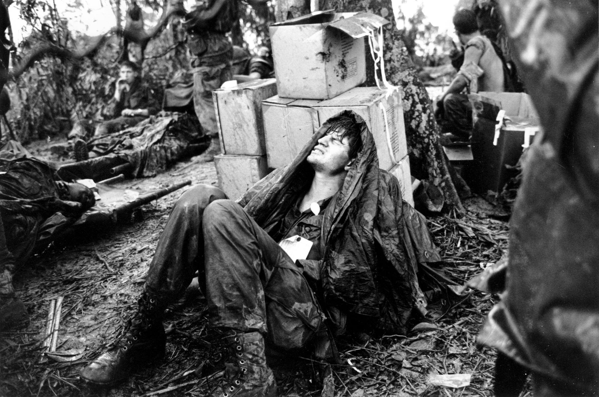 A wounded U.S. paratrooper grimaces in pain as he awaits medical evacuation at base camp in the A Shau Valley near the Laos border in South Vietnam on May 19, 1969.