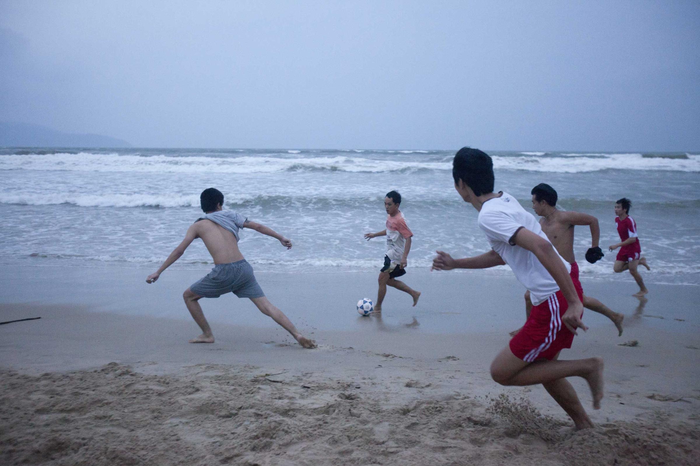 Students play football on the beach