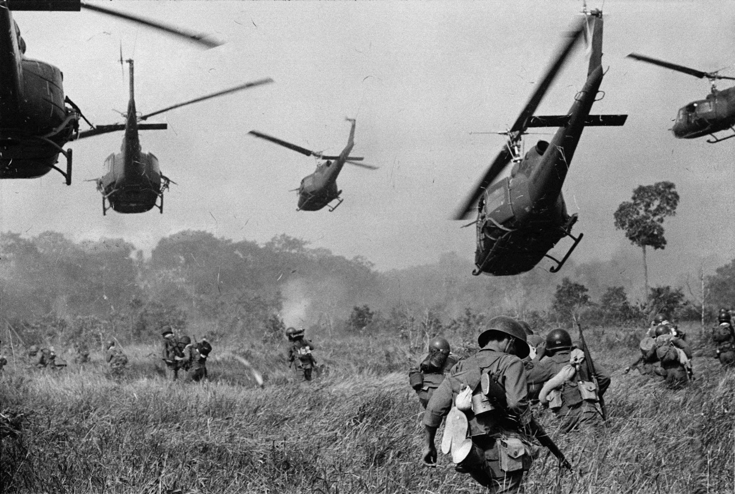 Hovering U.S. Army helicopters pour machine gun fire into the tree line to cover the advance of South Vietnamese ground troops in an attack on a Viet Cong camp 18 miles north of Tay Ninh, northwest of Saigon near the Cambodian border, in March 1965.