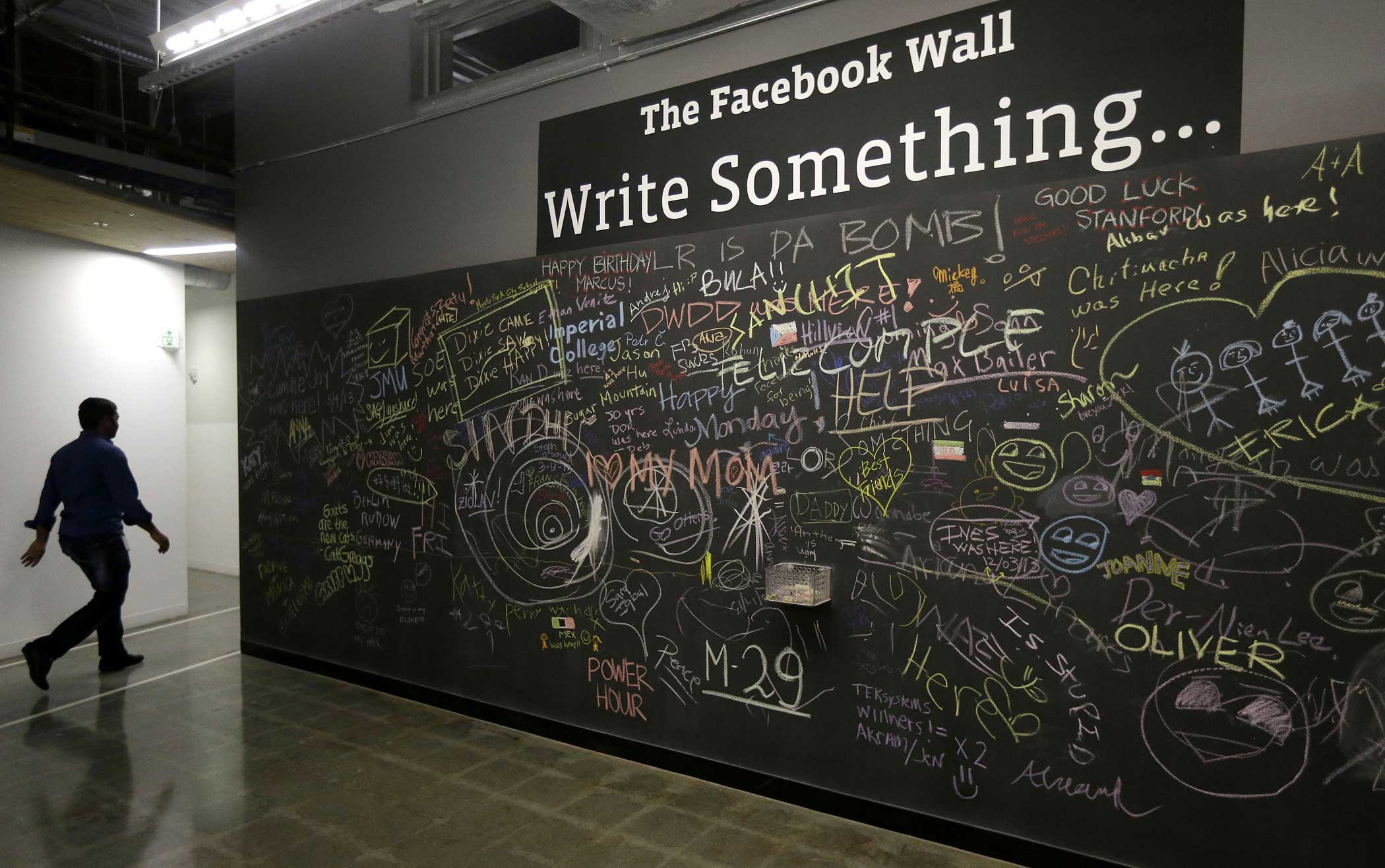 A Facebook employee walks past The Facebook Wall at the old Facebook headquarters in Menlo Park, Calif. on March 15, 2013.