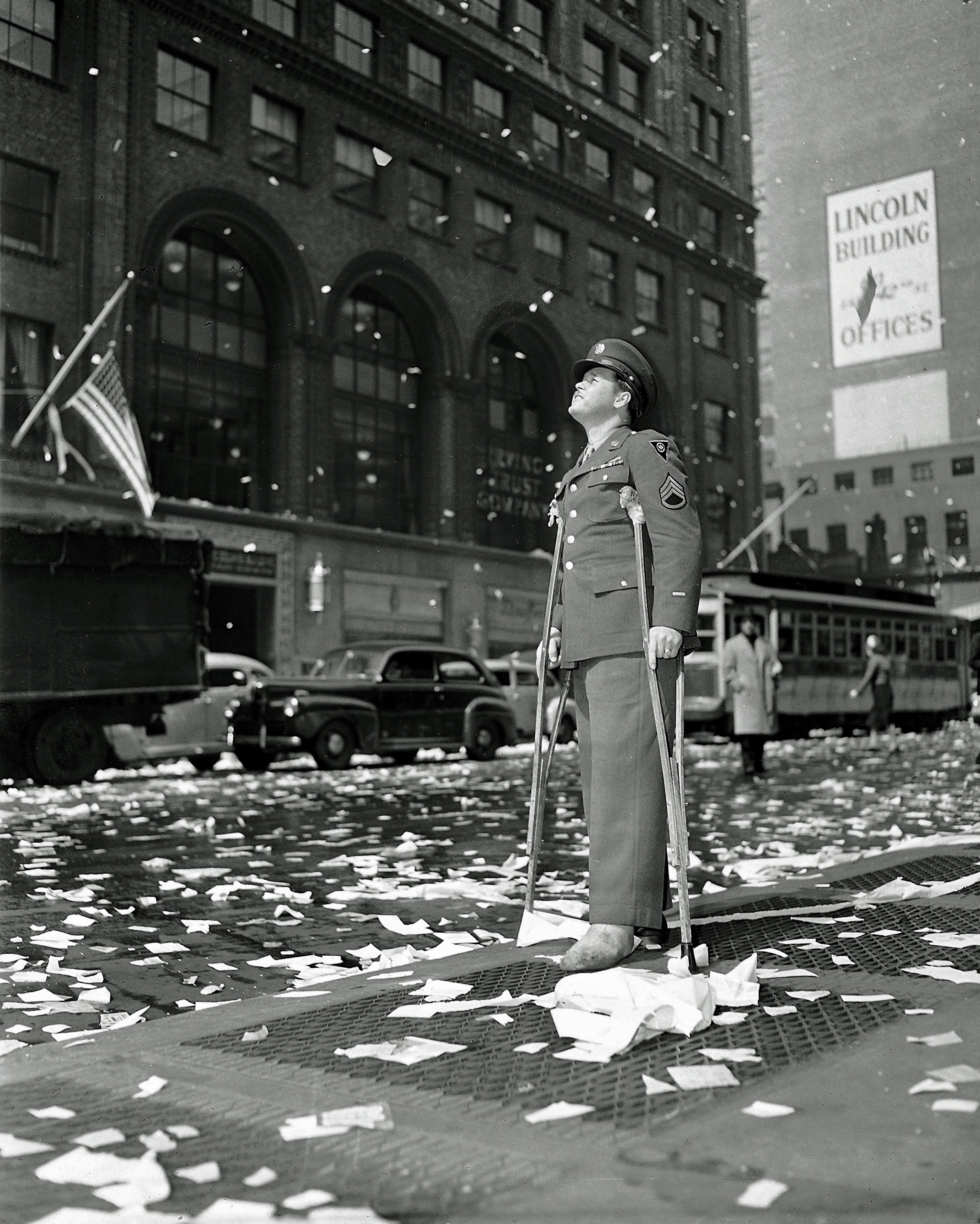 Staff Sgt. Arthur Moore of Buffalo, N.Y., who was wounded in Belgium, stands on 42nd Street near Grand Central Station in New York Monday, May 7, 1945 as New Yorkers celebrate news of VE Day, victory over Nazi Germany. (AP Photo)