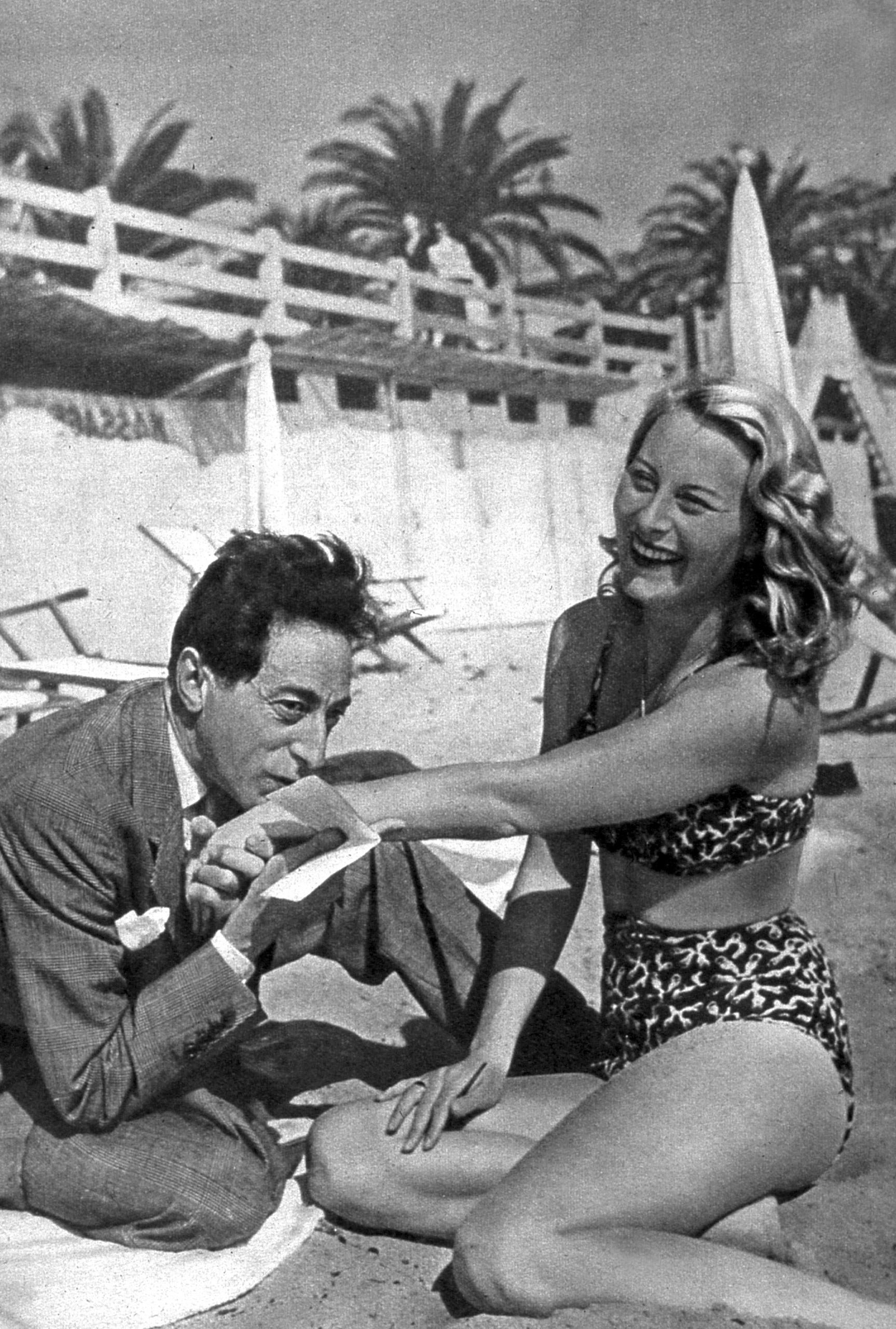 French actress Michele Morgan with artist and filmmaker Jean Cocteau on the beach during the Cannes Film Festival, 1946.