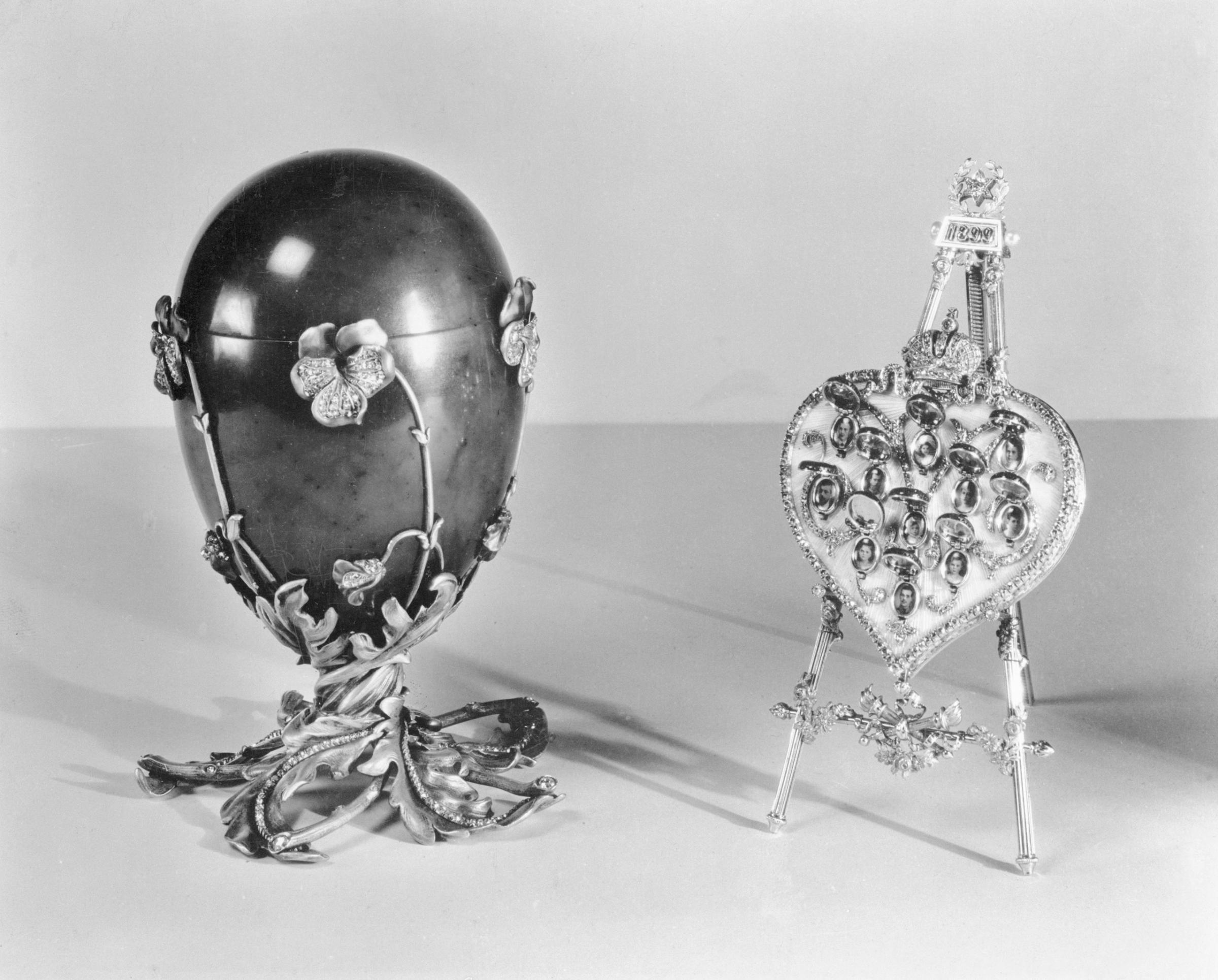 Russian Imperial Gems Shown In New York. Spinach jade Easter egg, decorated with pansies of enamel and diamonds, mounted on a pedestal of twisted gold leaves and twigs, also studded with diamonds. It contains a folding easel in the shape of a diamond-studded heart, covered with translucent enamel. The heart is surmounted by the Imperial Crown in diamonds. It was presented by Czar Nicholas II to his mother, the Dowager Empress Marie, at Easter in 1899. The work of Carl Faberge, late court jeweler, it is being exhibited with other Russian Imperial jewels and art treasures at the Hammer Galleries in New York City, 1937.