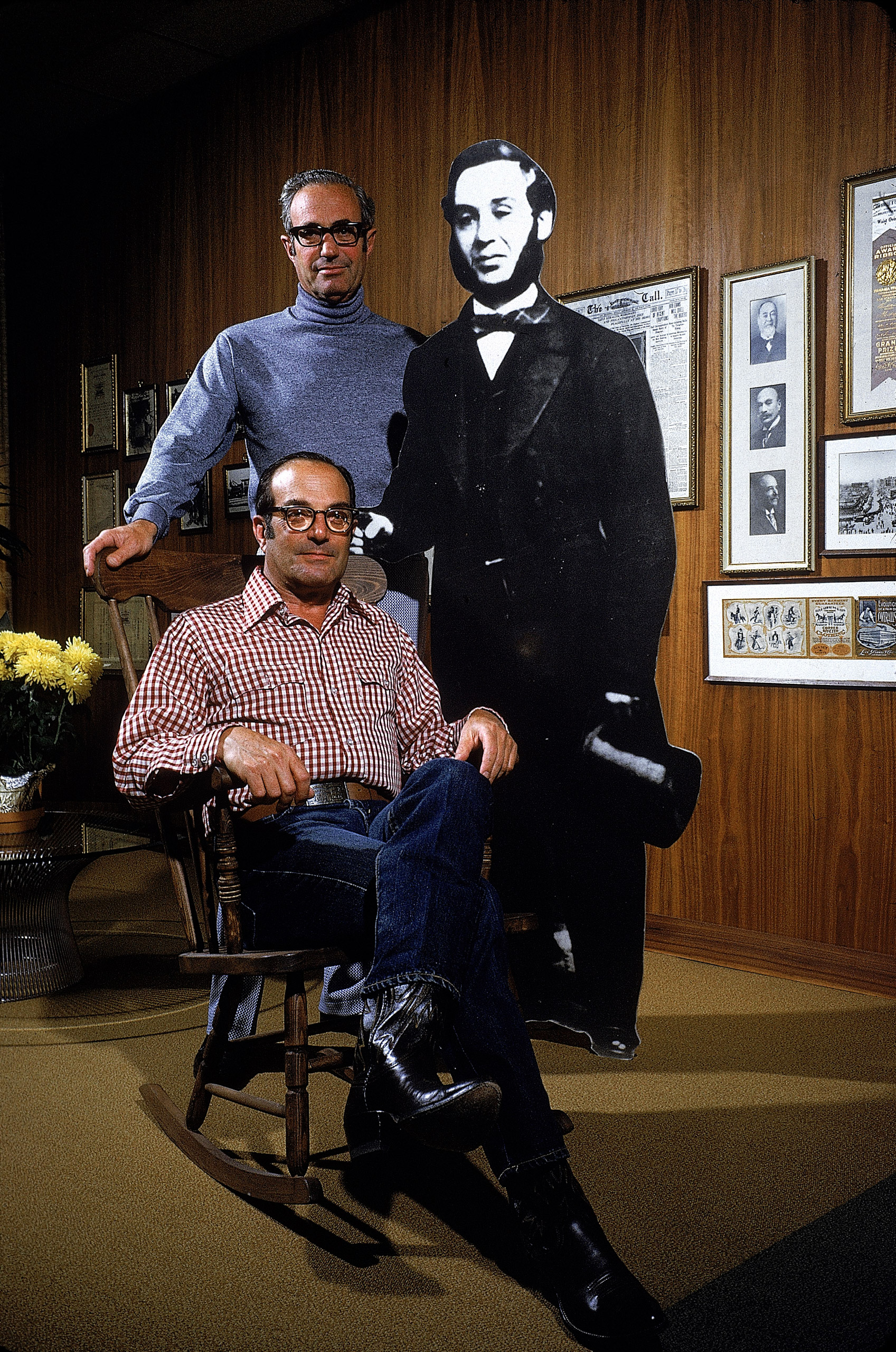 Peter Haas, President of Levi Strauss (seated) and former company president, his brother Walter (standing), next to cut-out of company founder, 1972.