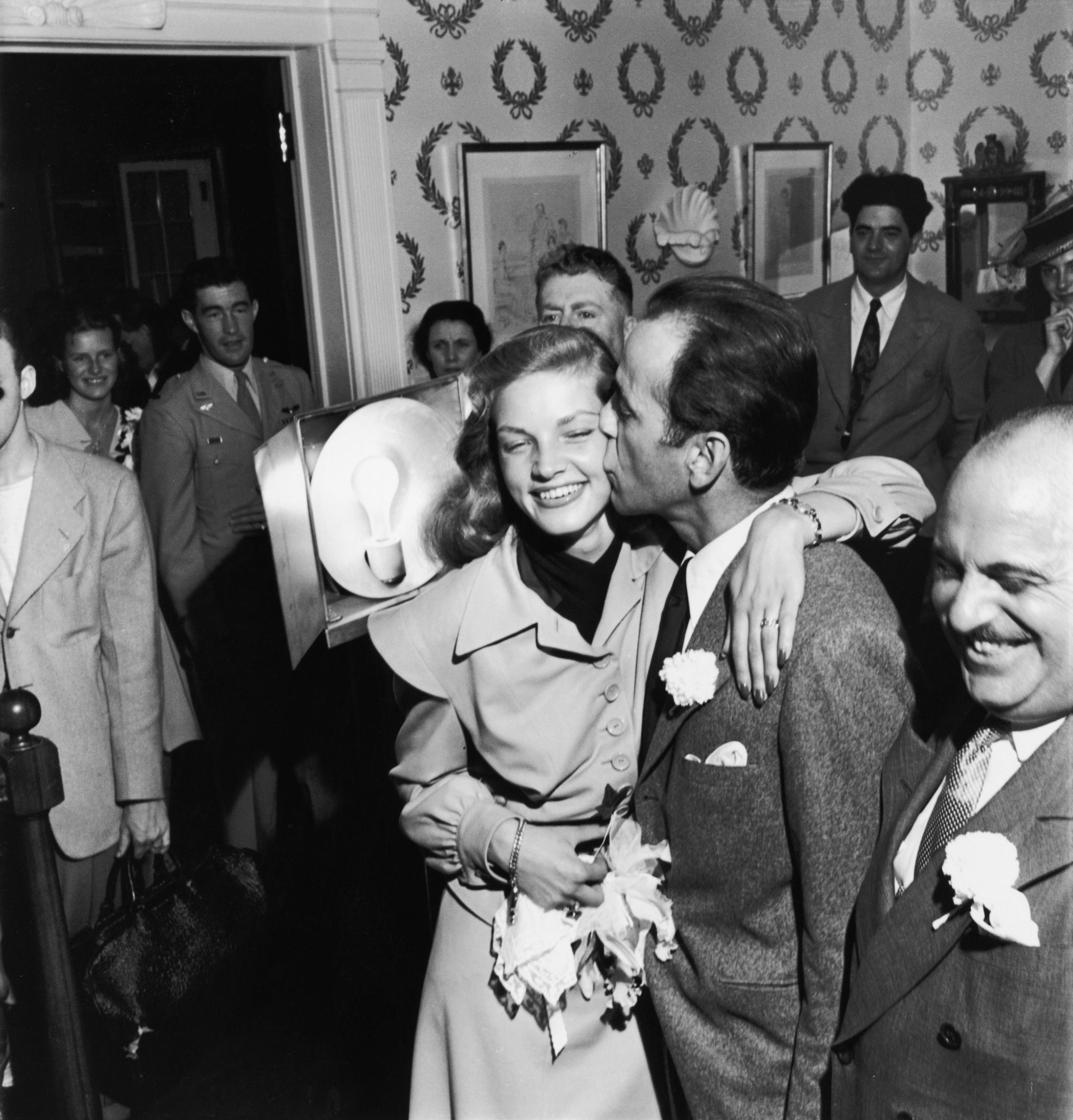Newlywed actors Humphrey Bogart and Lauren Bacall attending wedding reception at the home of novelist Louis Bromfeld.