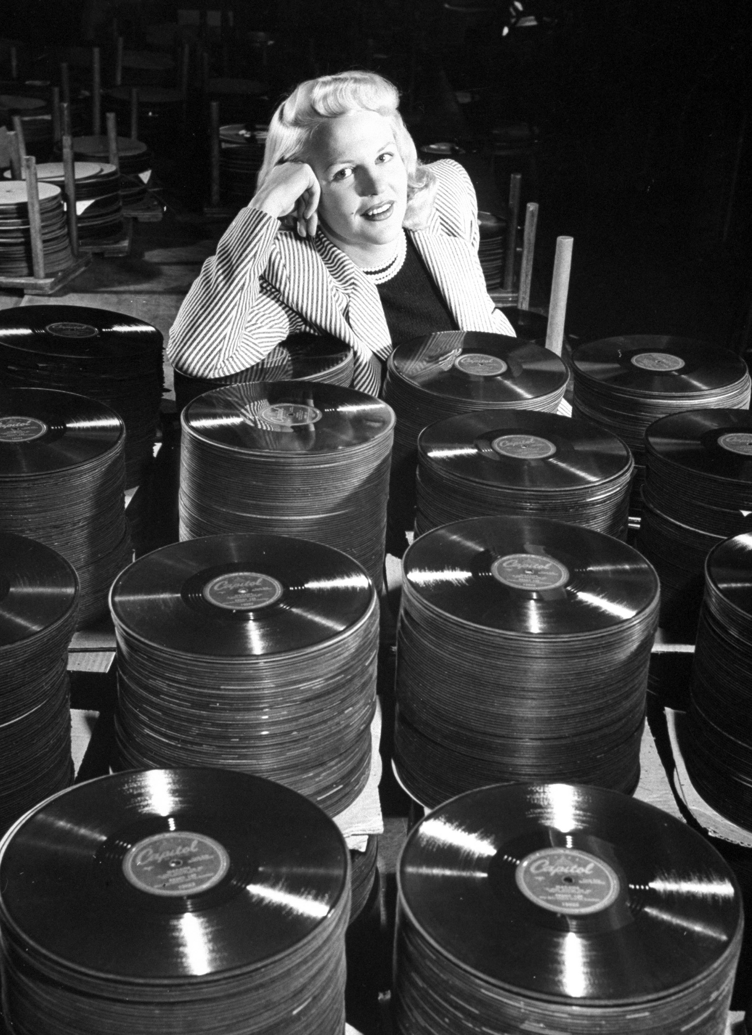 Singer Peggy Lee leans on a stack of records of her hit tune "Mañana." This record alone should bring in $75,000 in royalties in 1948.