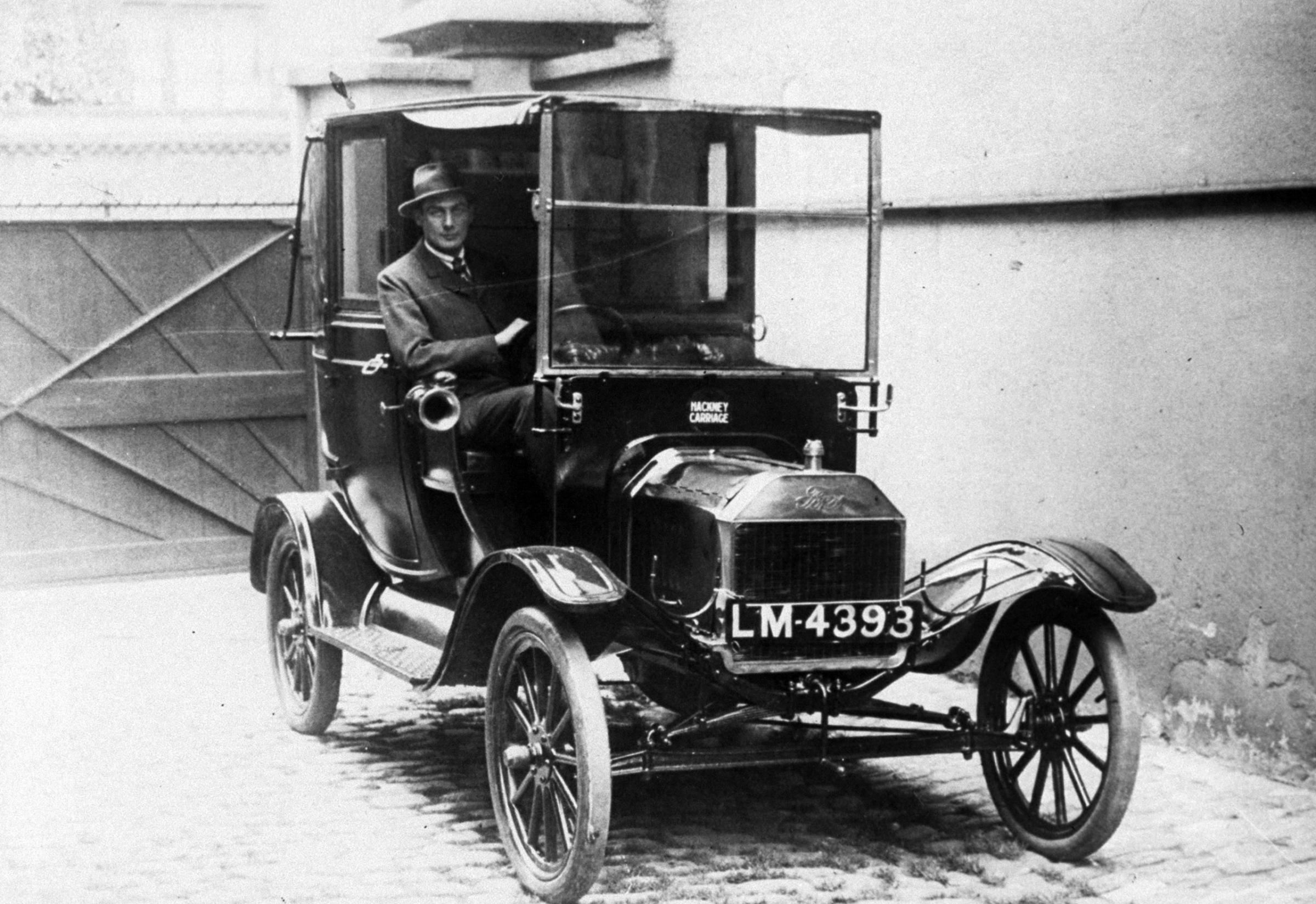 Driver behind wheel of a 1912 Ford Model T taxi.