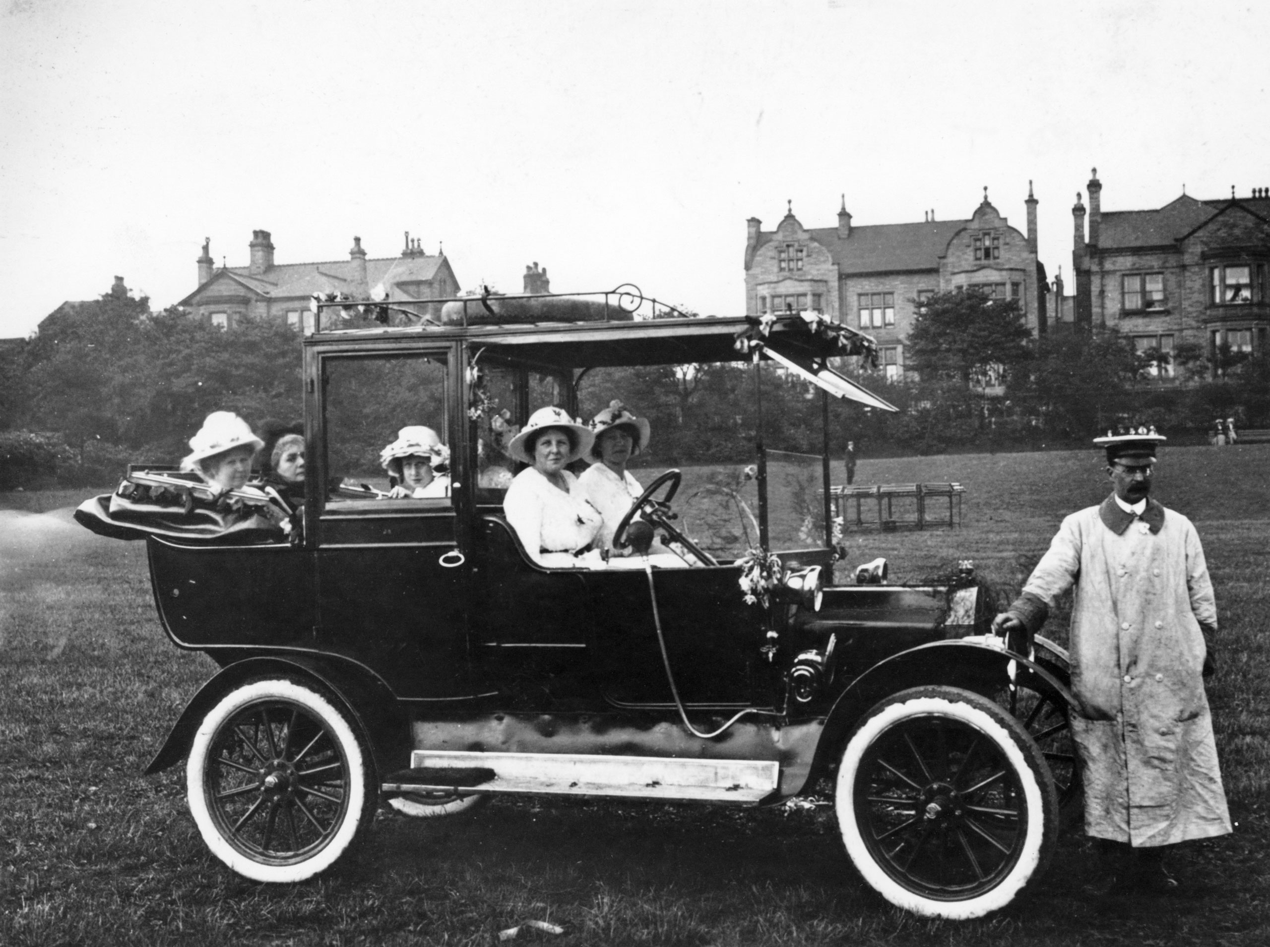 Ladies in a Model T Ford in 1914. Their chauffeur is standing in front of the car.