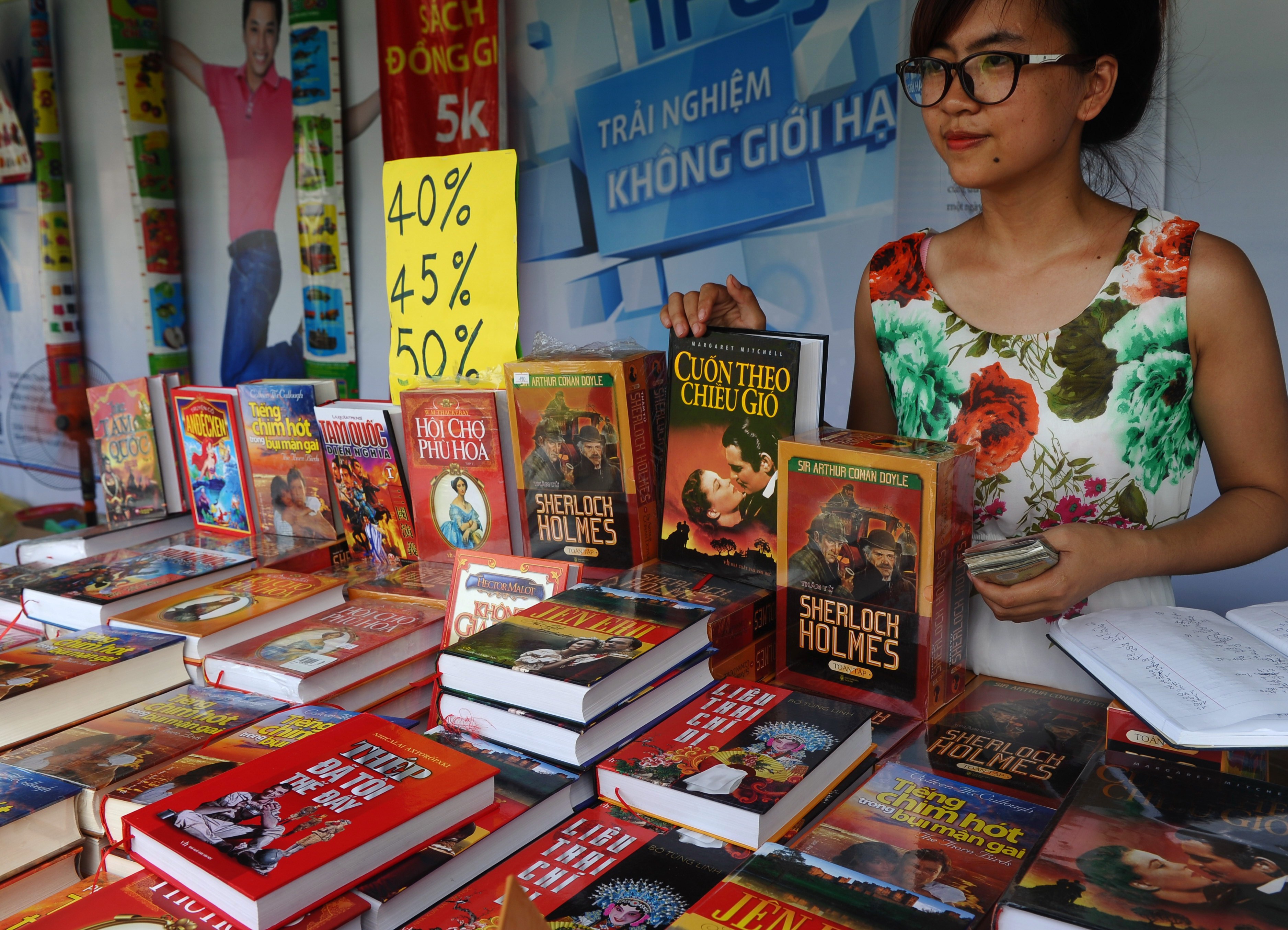 A publishing house employee stands at a booth selling discount foreign novels at a book festival in Hanoi on September 30, 2014