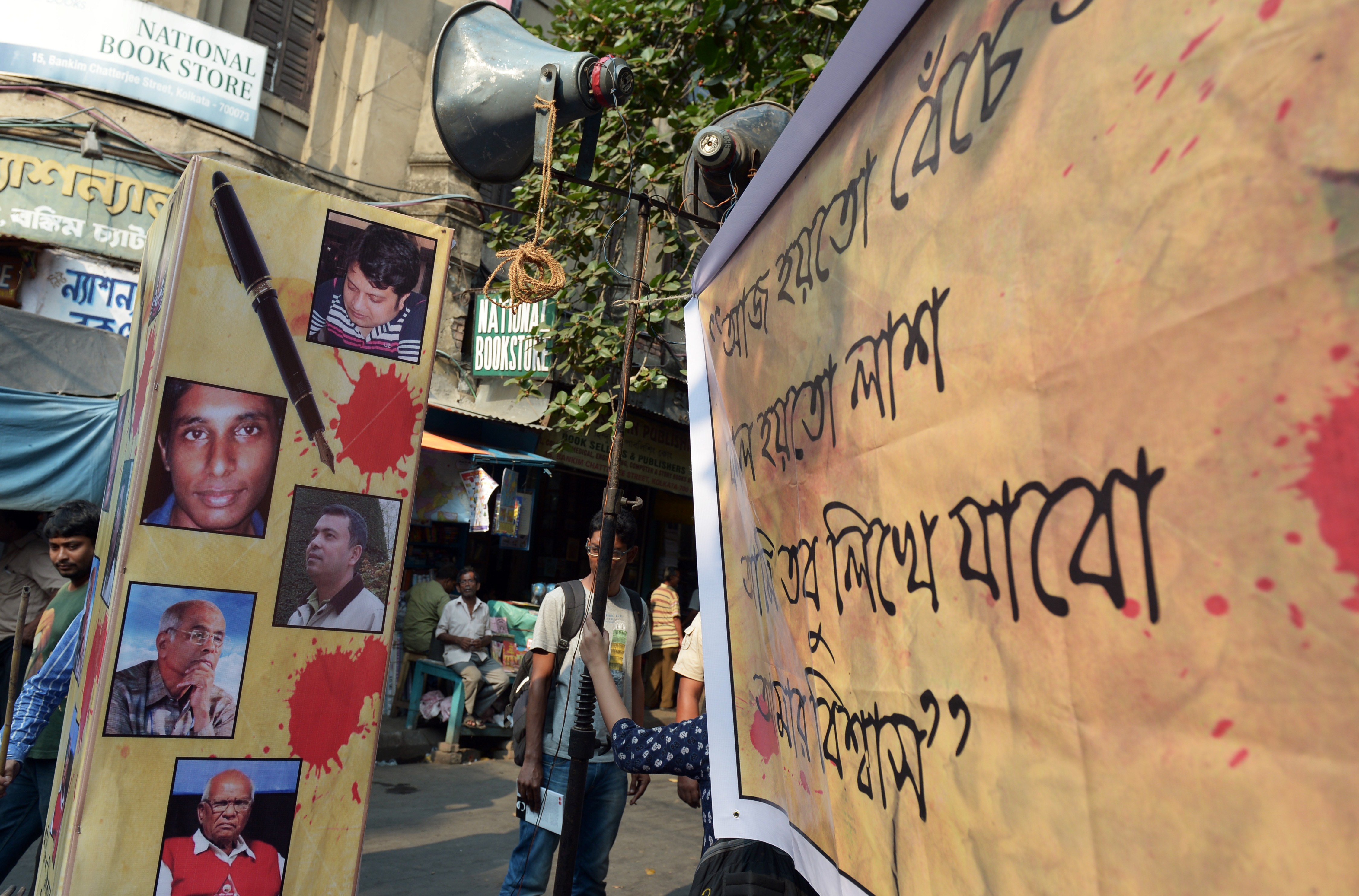 An Indian student looks from behind a poster with pictures of recently killed Bangladeshi bloggers during a protest meeting organized to pay homage in Kolkata on May 16, 2015. (DIBYANGSHU SARKAR—AFP/Getty Images)