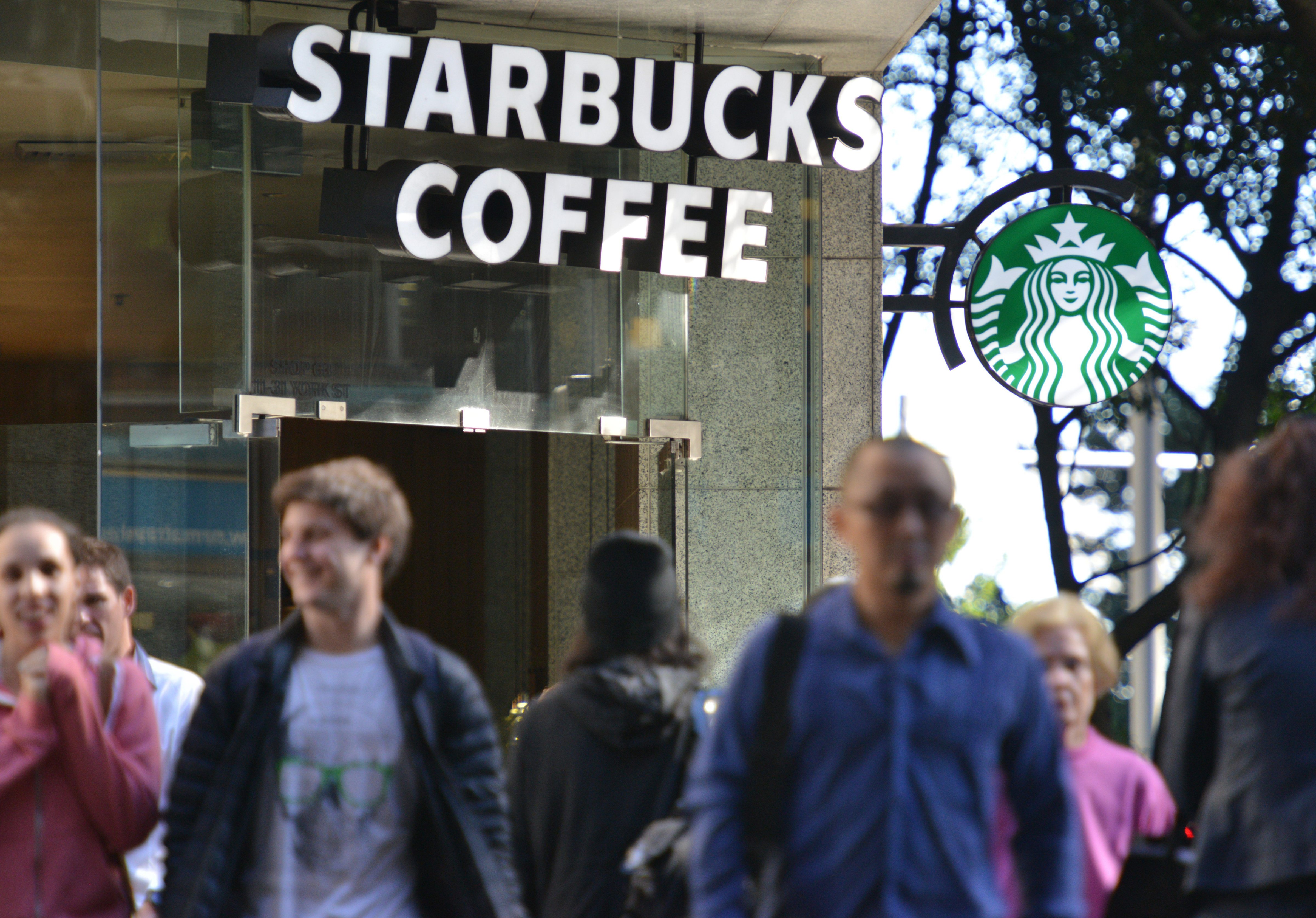 Pedestrians cross a street in front of a Starbucks coffee house in Sydney on May 28, 2014. (Peter Parks&mdash;AFP/Getty Images)