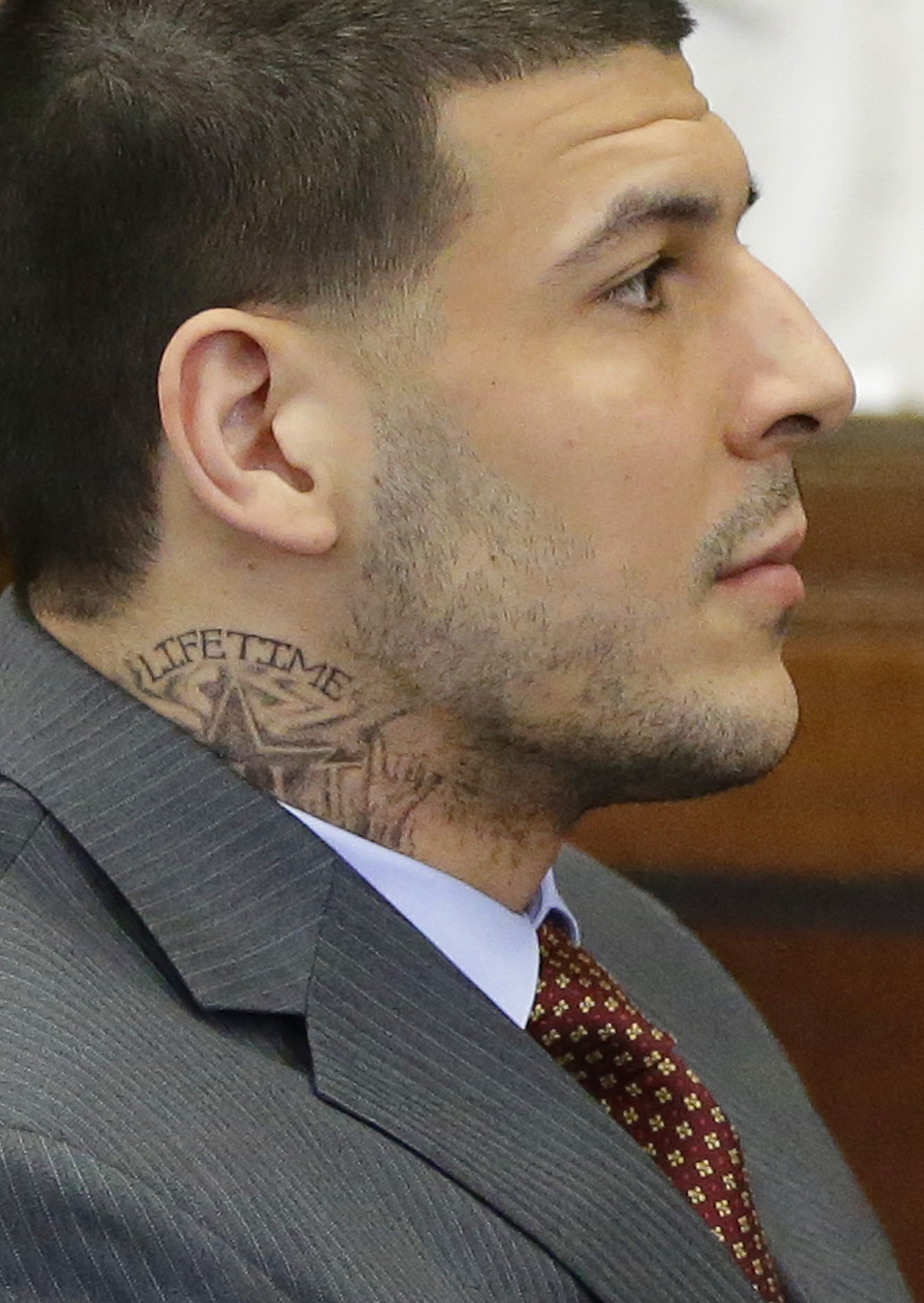 Sporting a new neck tattoo, former New England Patriots NFL football player Aaron Hernandez sits at the defense table during his arraignment at Suffolk Superior Court on May 21, 2015 in Boston. (Stephan Savoia—AP)