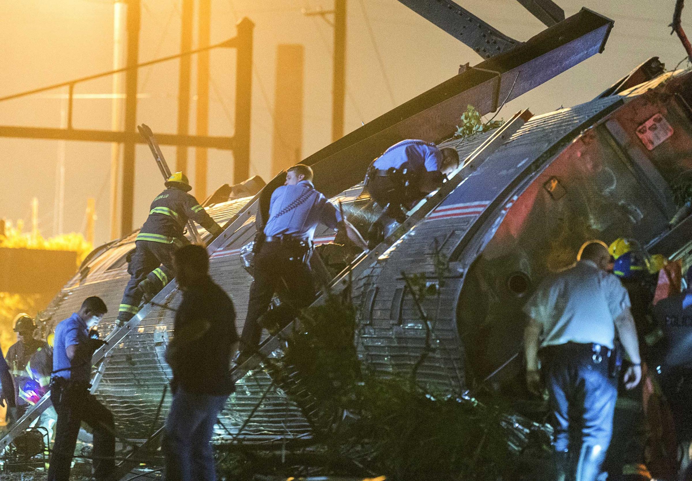 Rescue workers climb into the wreckage of a derailed Amtrak train to search for victims in Philadelphia on May 12, 2015.