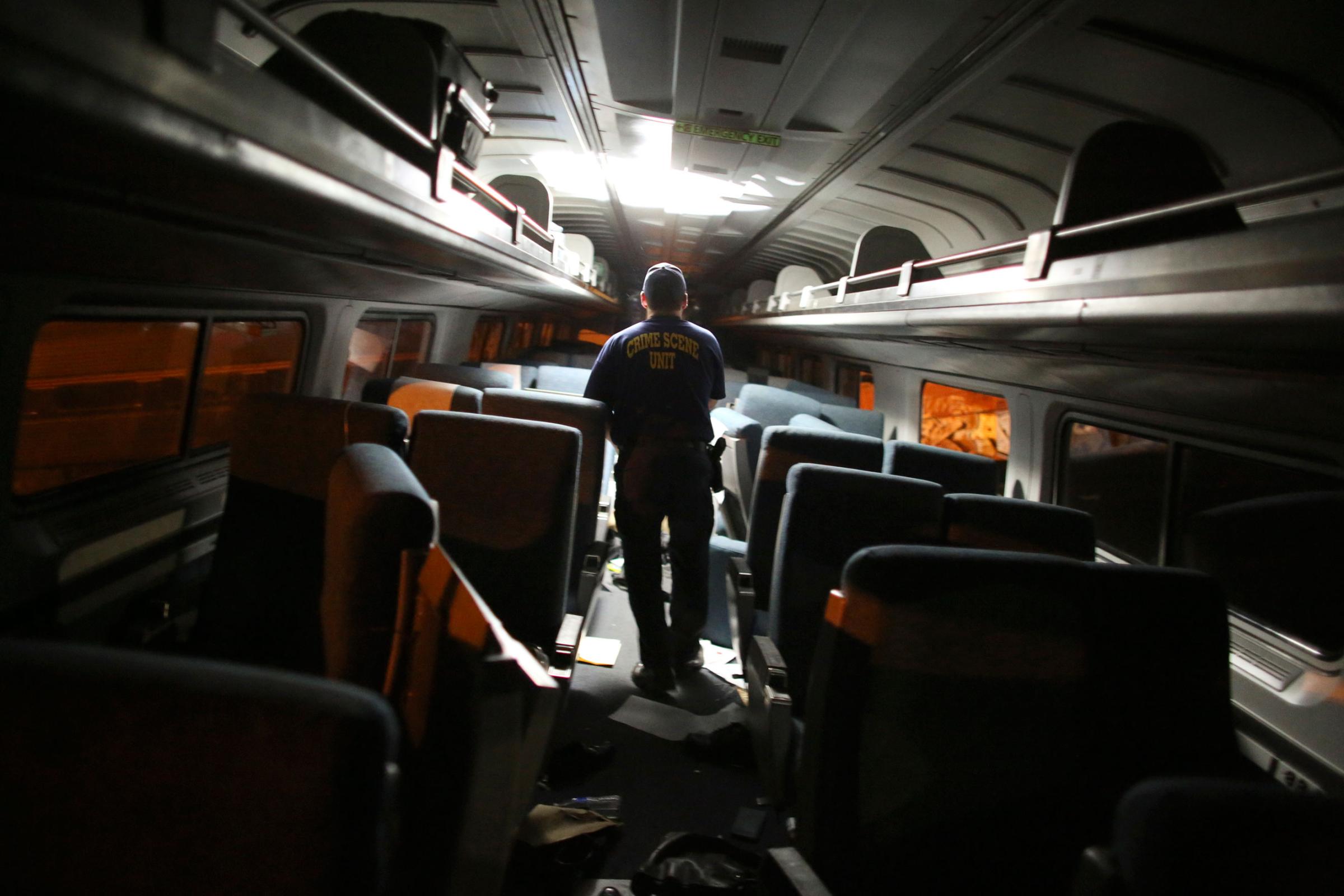 A crime scene investigator looks inside a train car after a train wreck on May 12, 2015, in Philadelphia.