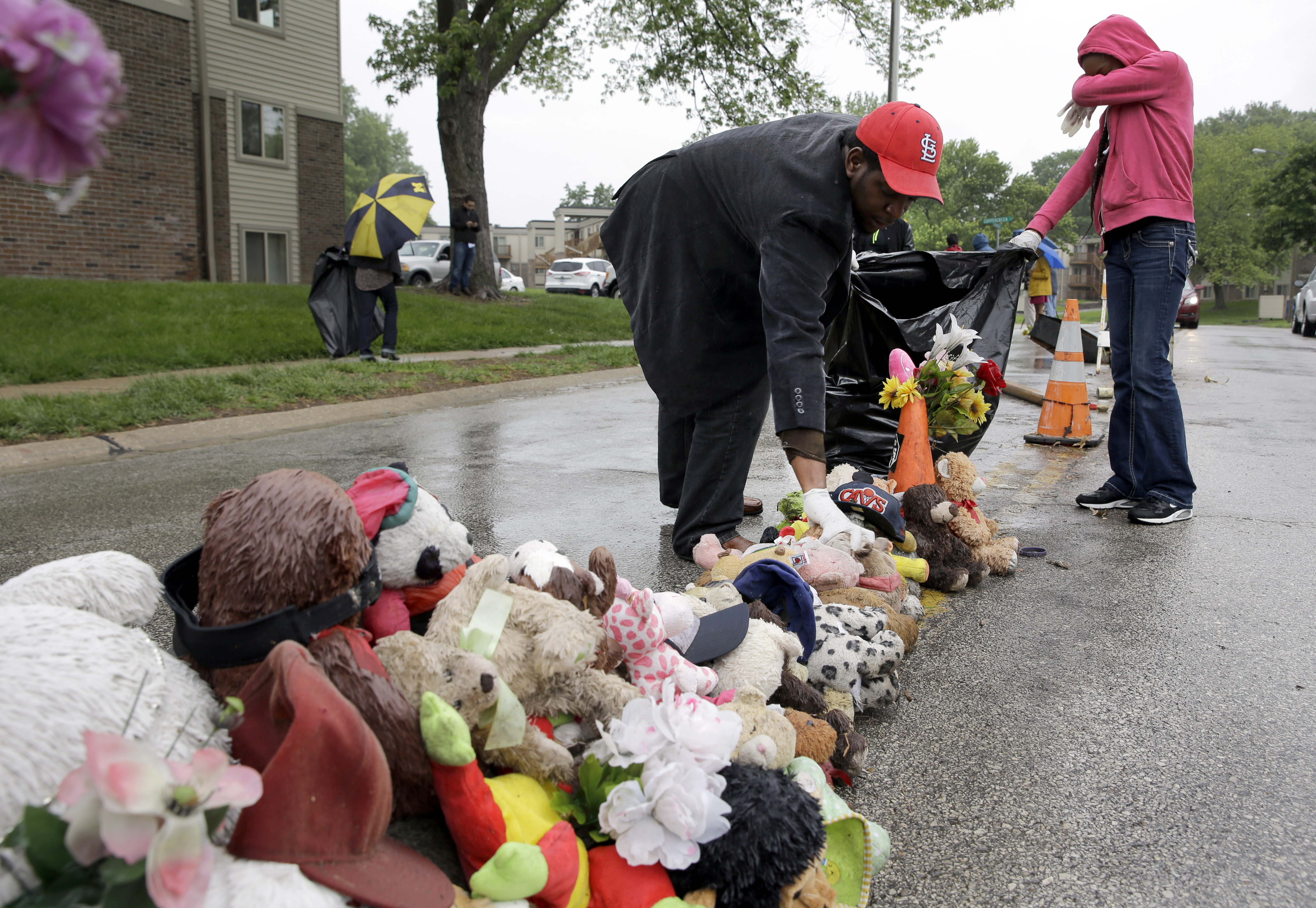 Volunteers Cheyenne Green, right, and Derrick Robinson help remove items left at a makeshift memorial to Michael Brown Wednesday, May 20, 2015, in Ferguson, Mo.