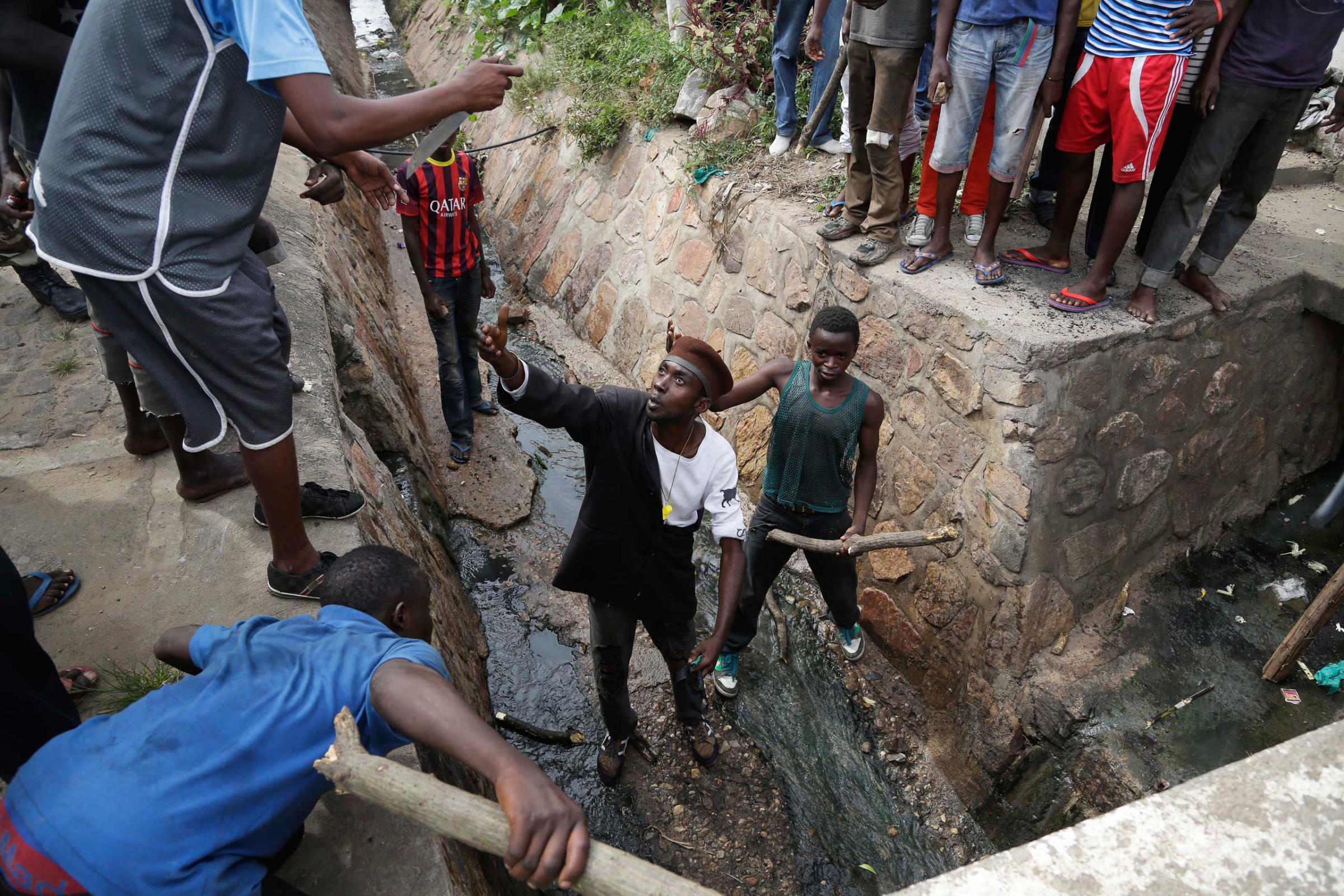 Demonstrators prepare to flush out Niyonzima who escaped a lynching by escaping into a sewer.