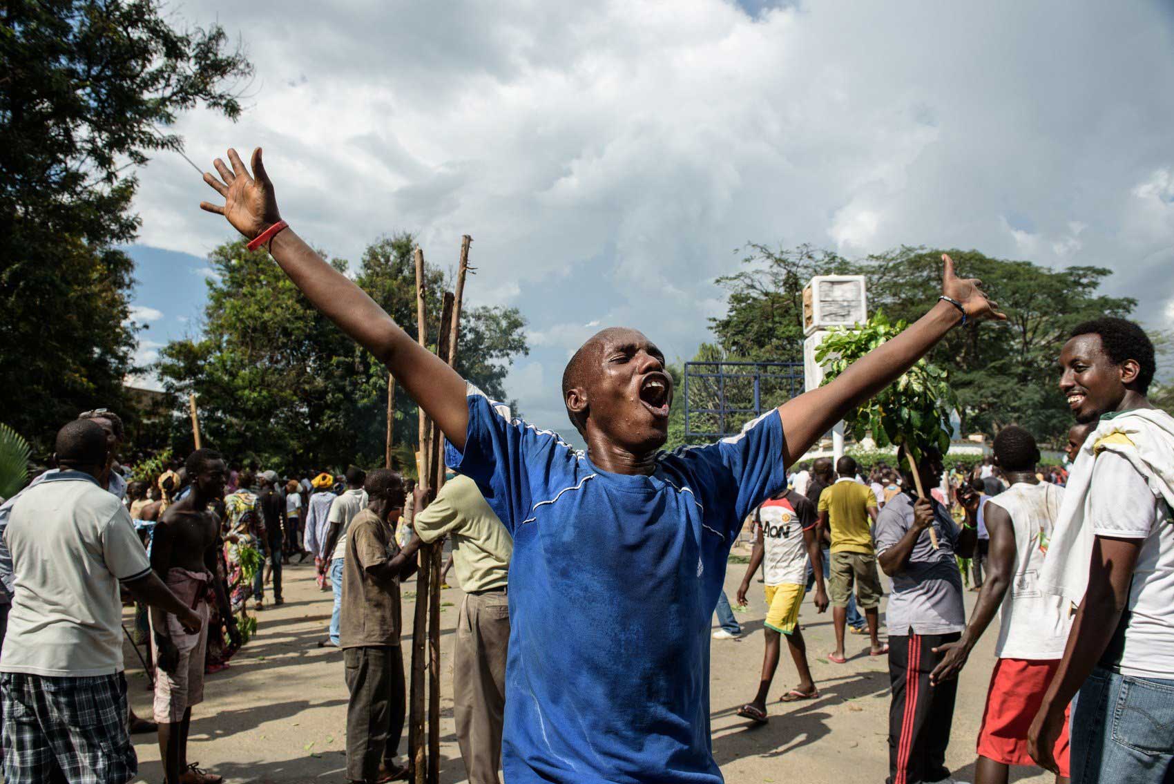 A man raises his arms as people celebrate in the streets of Bujumbura following the radio announcement by Major General Godefroid Niyombare that President Pierre Nkurunziza was overthrown on May 13, 2015.