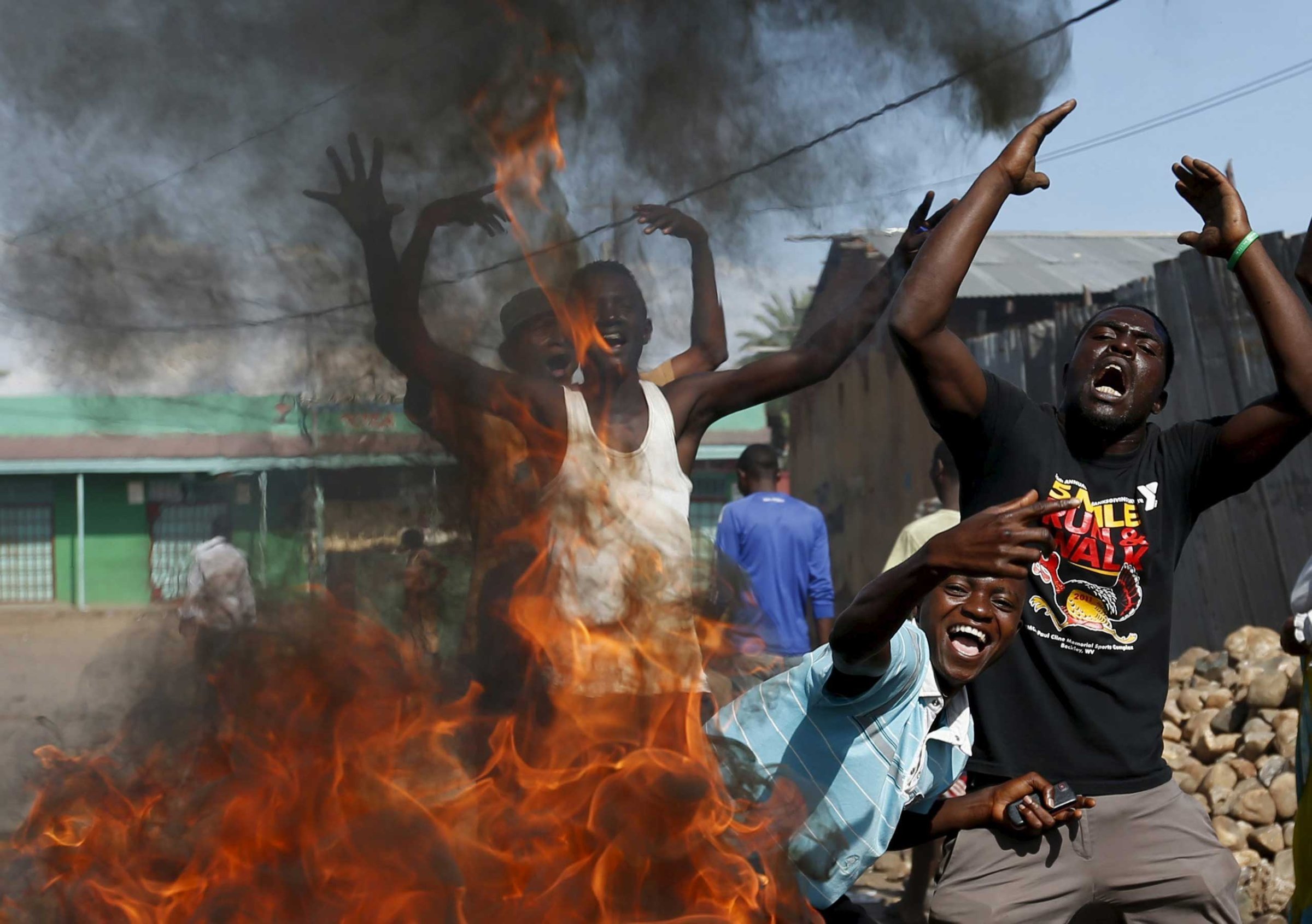 Protesters, who are against President Pierre Nkurunziza's decision to run for a third term, gesture in front of a burning barricade in Bujumbura, Burundi on May 14, 2015.