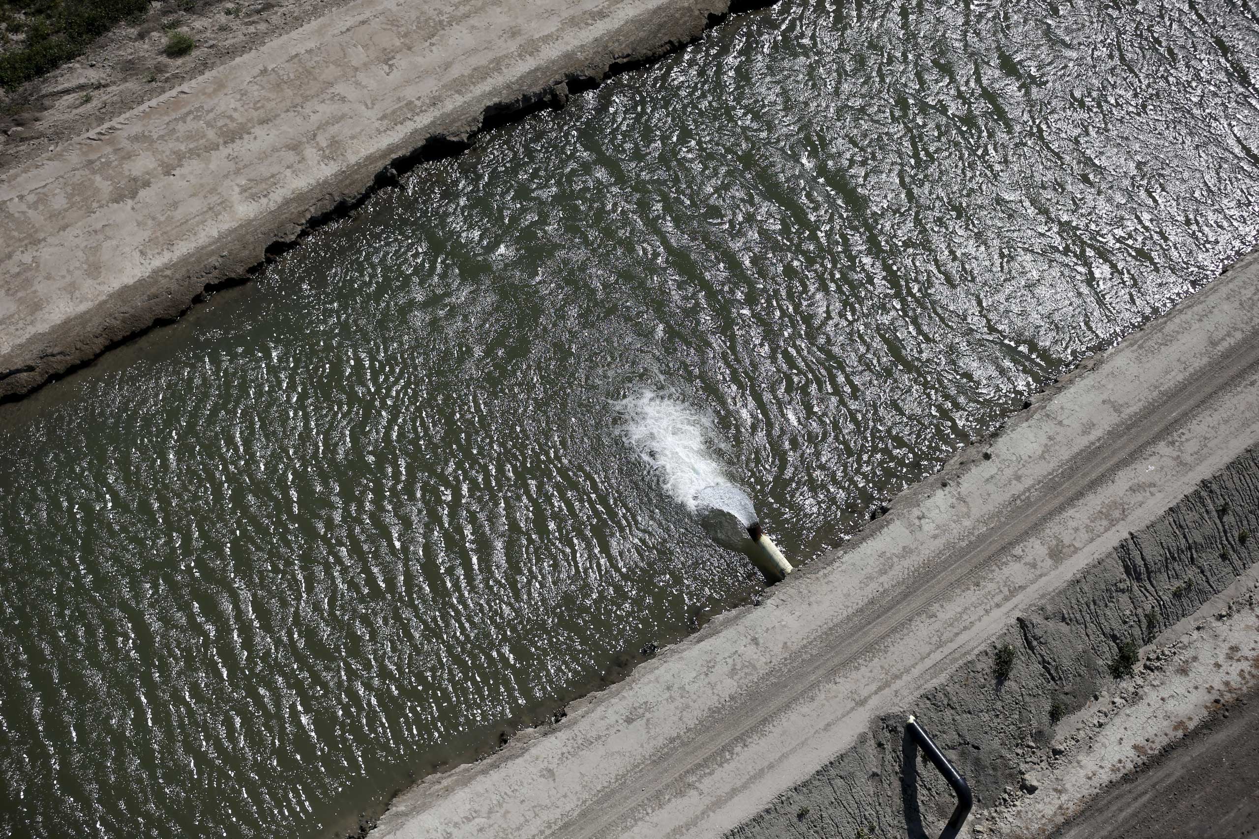 Central Valley farmers have witnessed land sinking by as much as 3 feet, San Francisco Gate reports, as water agencies tap underground reservoirs at unprecedented depths. Water pours into a canal in Los Banos, Calif., May 5, 2015.