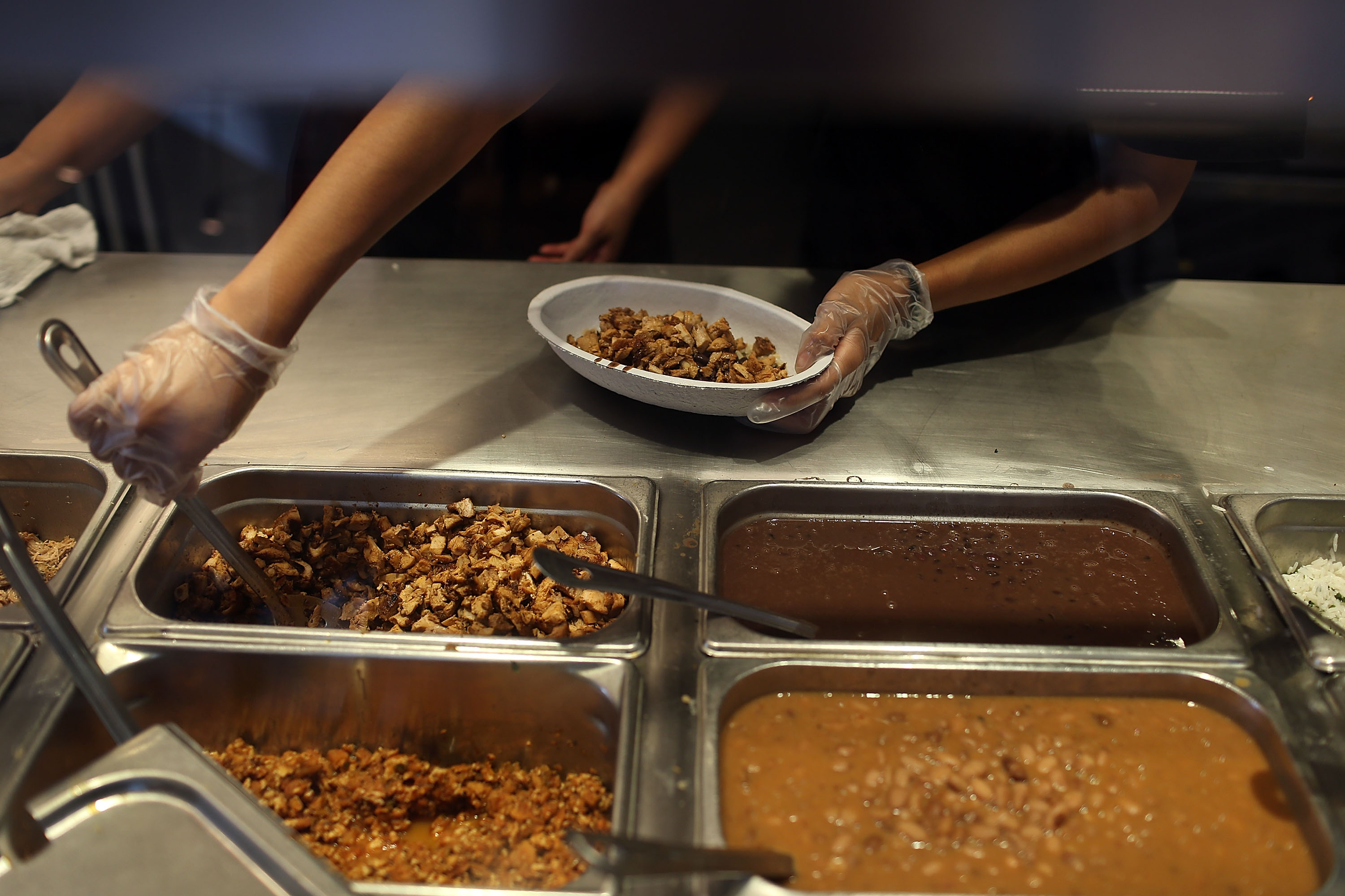 Chipotle restaurant workers fill orders for customers on the day that the company announced it will only use non-GMO ingredients in its food on April 27, 2015 in Miami, Florida. (Joe Raedle—Getty Images)