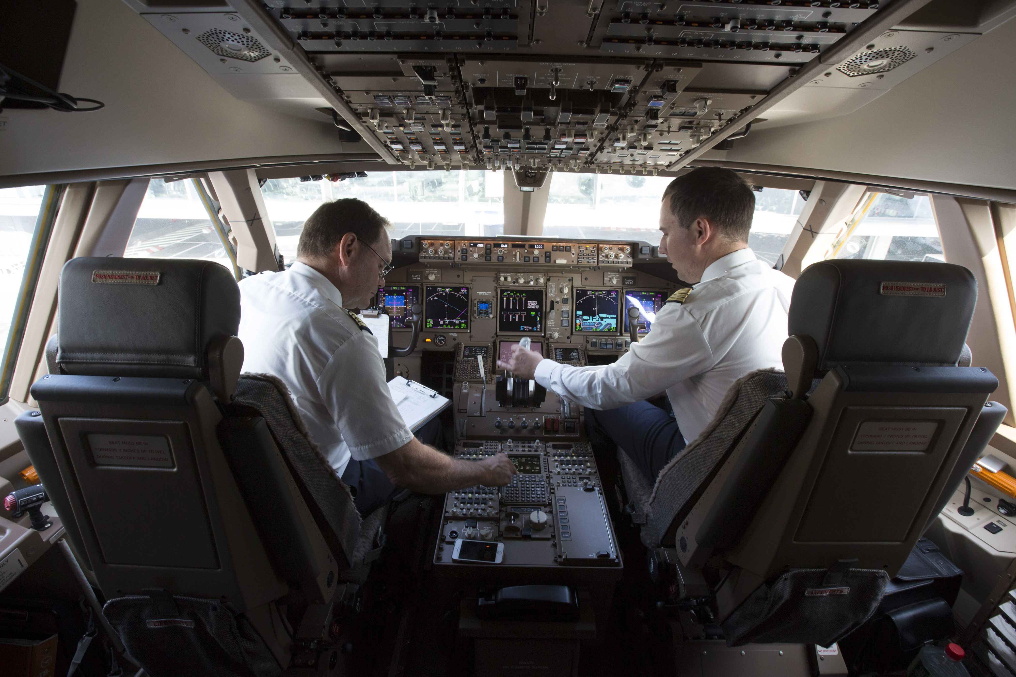 A Deutsche Lufthansa AG pilot, left, and co-pilot sit in the cockpit of a Boeing 747-8 passenger aircraft on Oct. 2, 2014. (Bloomberg via Getty Images)