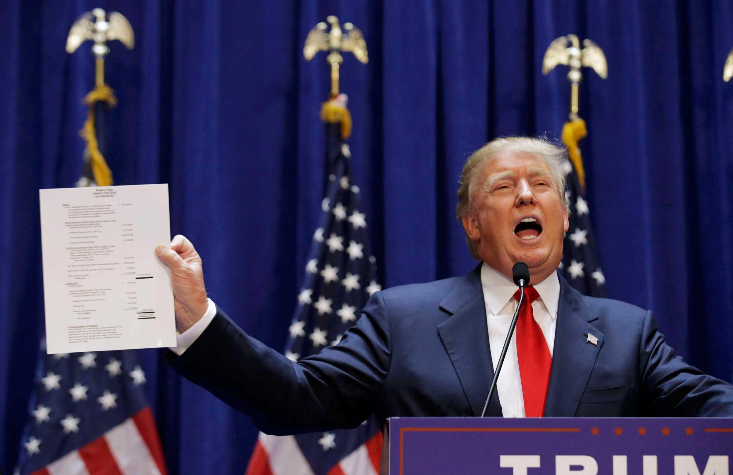 U.S. Republican presidential candidate Trump holds up his financial statement as he formally announces his campaign for the 2016 Republican presidential nomination at Trump Tower in New York