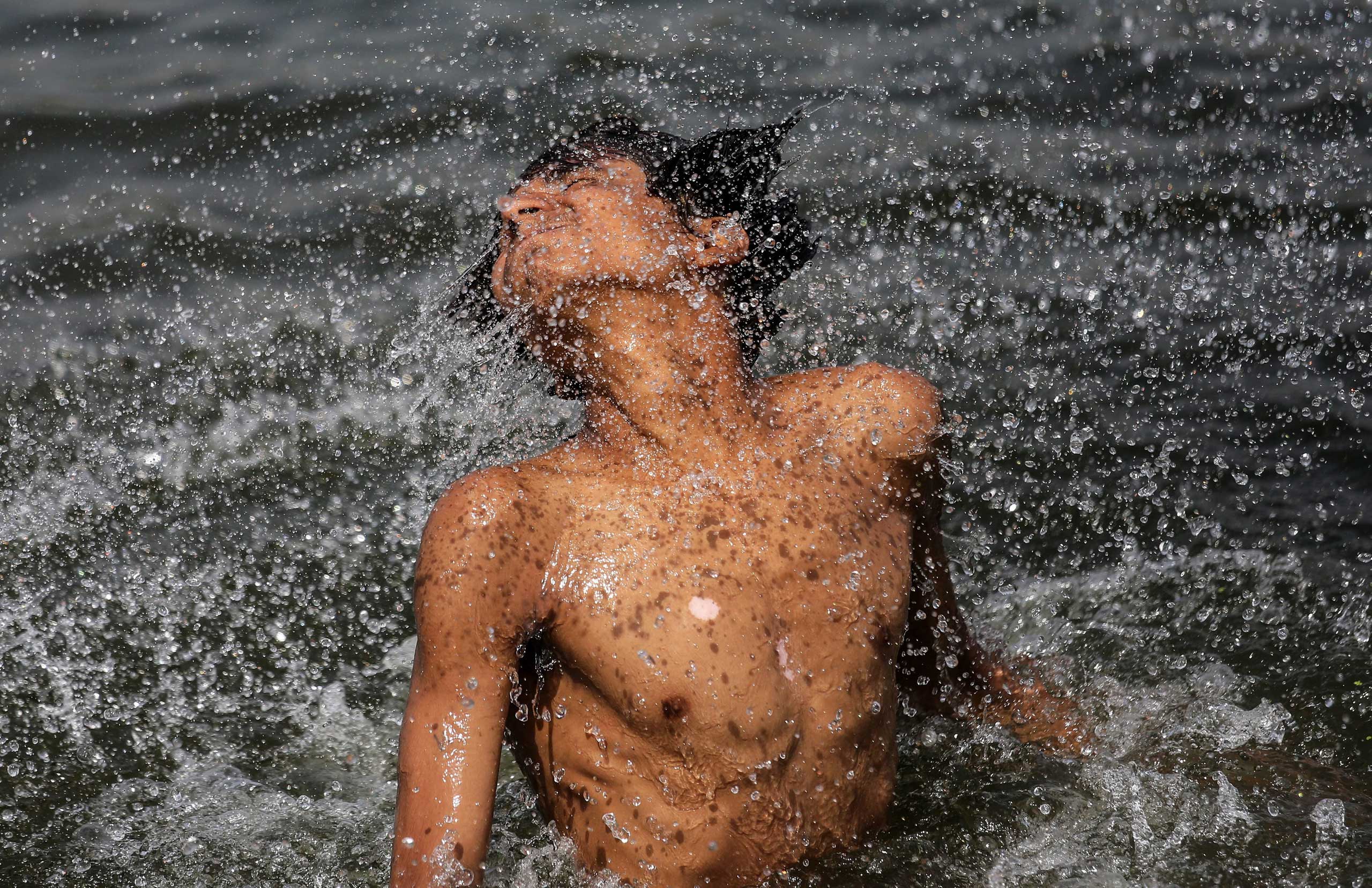 A youth frolics in the Sabarmati river as he cools himself off on a hot afternoon in Ahmedabad, India on May 26, 2015.