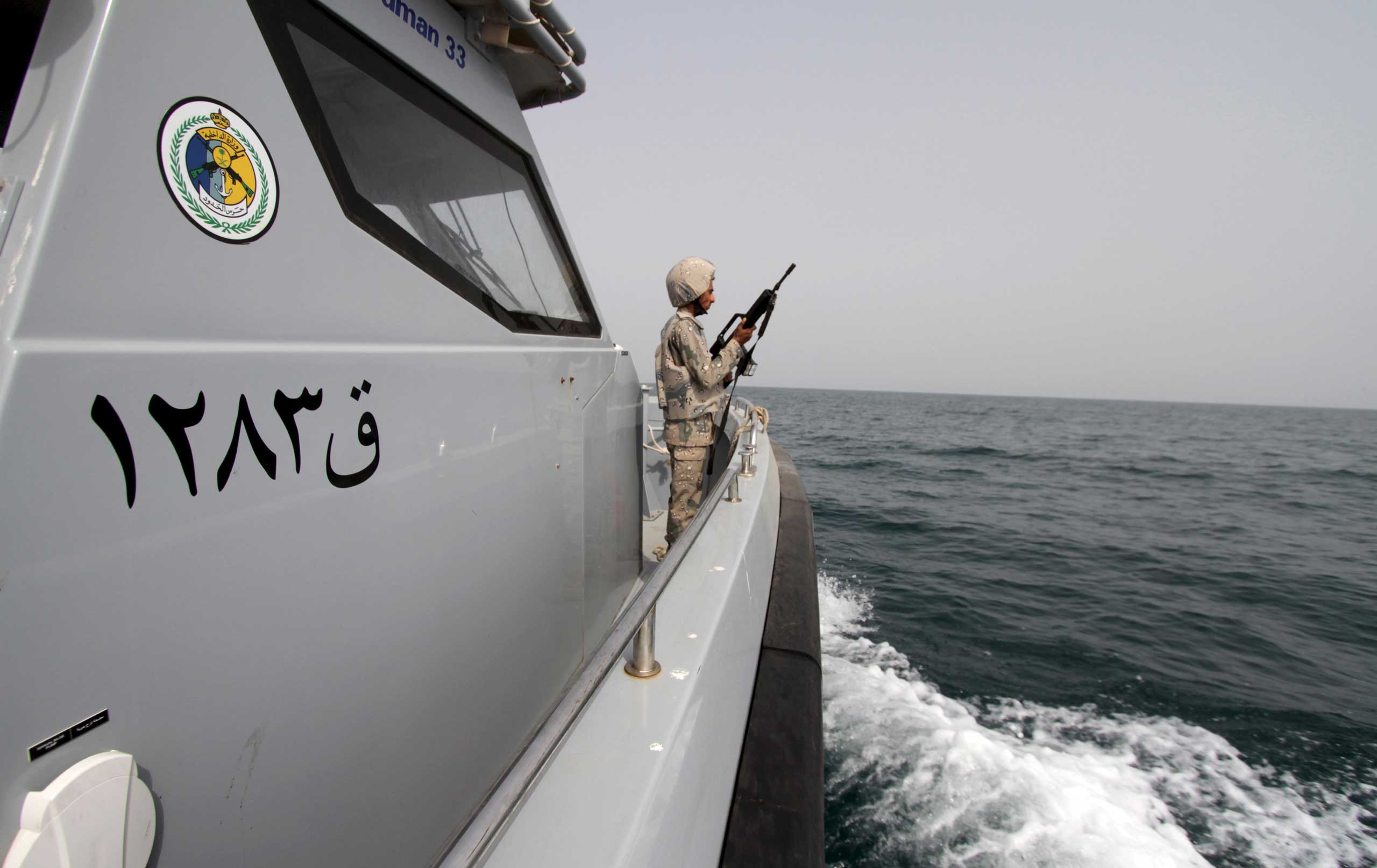 A Saudi border guard watches as he stands in a boat off the coast of the Red Sea on Saudi Arabia's maritime border with Yemen, near Jizan April 8, 2015.