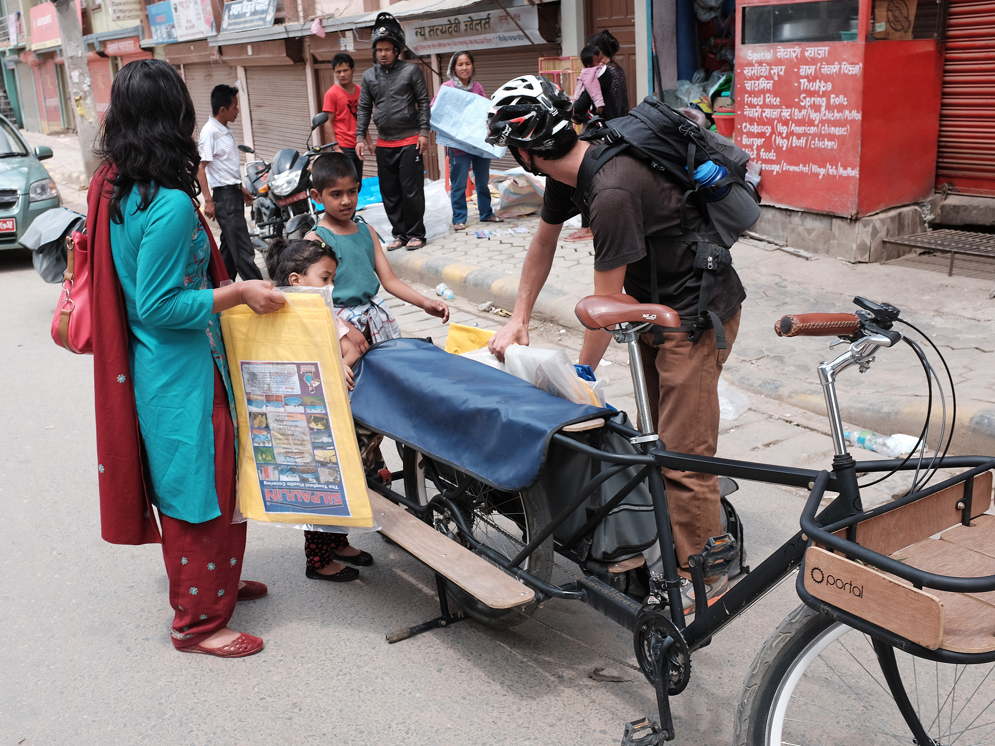 Mountain bike team member hands out tarpaulin in villages in need of relief after the Nepal earthquake of April 25, 2015