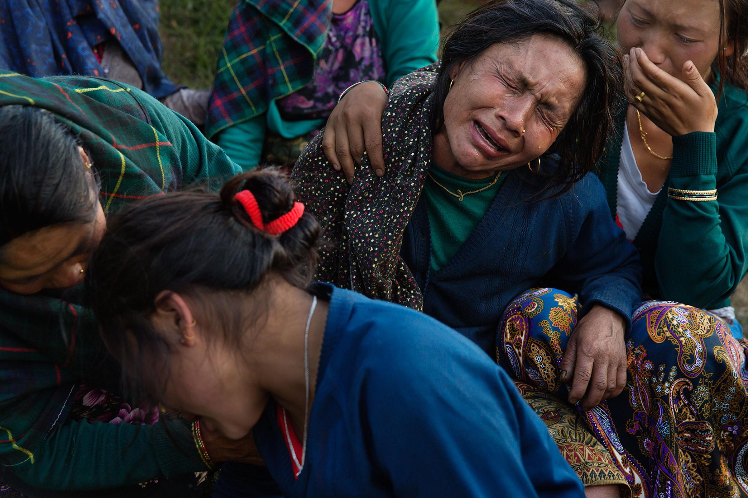 Nepal earthquake. Barpak, the epicenter of the earthquake. Funeral of Pur Bahadur Gurung, 26, who had just been dug out of the rubble. Saainli Gurung, his mother weeping. Scenes of villagers salvaging building materials and personal possessions. Dhan Raj Ghale, 30, dressed in mourning garb after the death of his wite, salvaging buildings materials and possessions from his house. by James Nachtwey