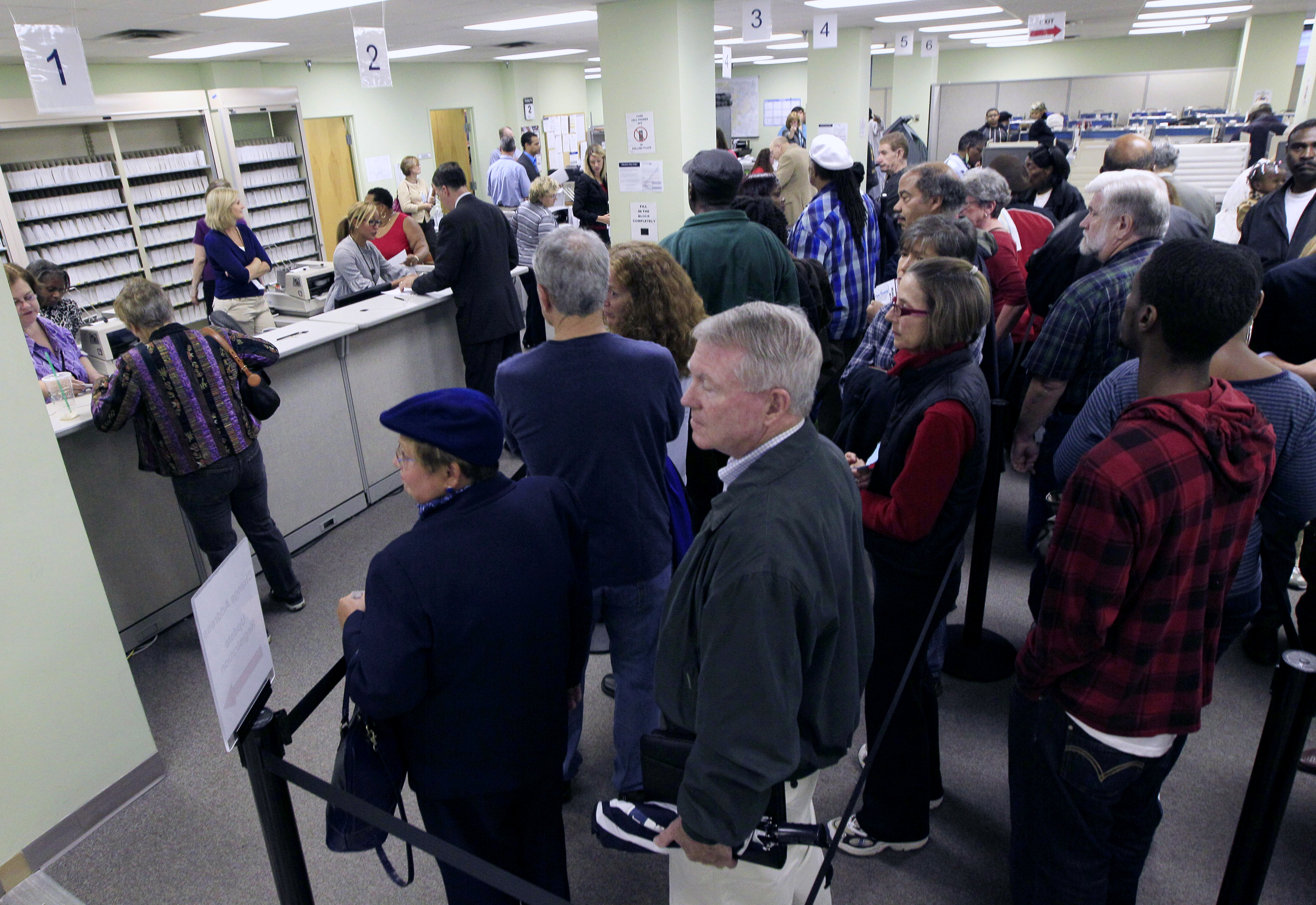 This Oct. 2, 2012 file photo shows voters waiting in line to pick up their ballots inside the Hamilton County Board of Elections after it opened for early voting, in Cincinnati.