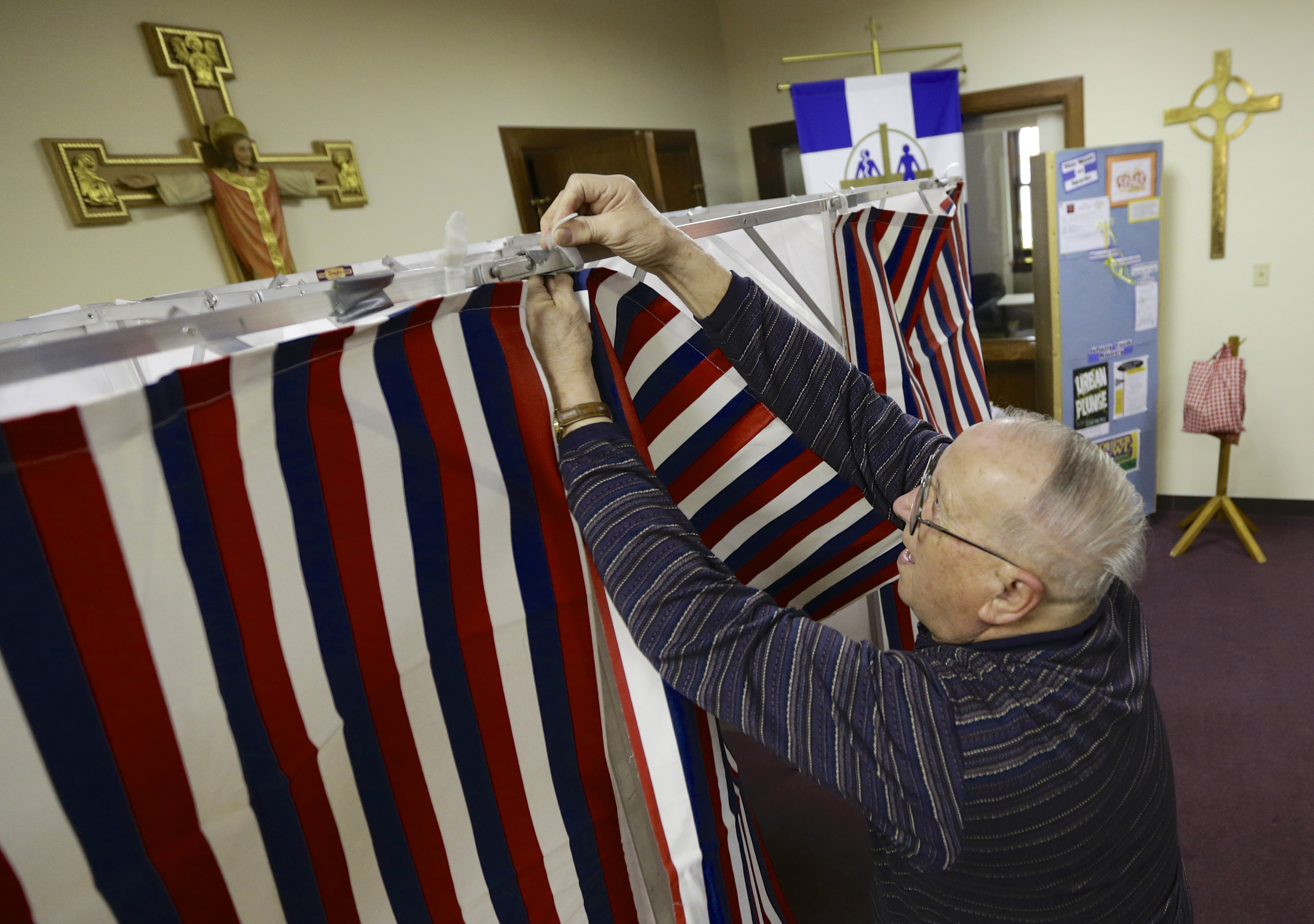 Election official Robert Buresh attaches the curtain to a polling booth at the Salem Lutheran Church polling station in Fremont, Neb., on Feb. 11, 2014. (Nati Harnik—AP)
