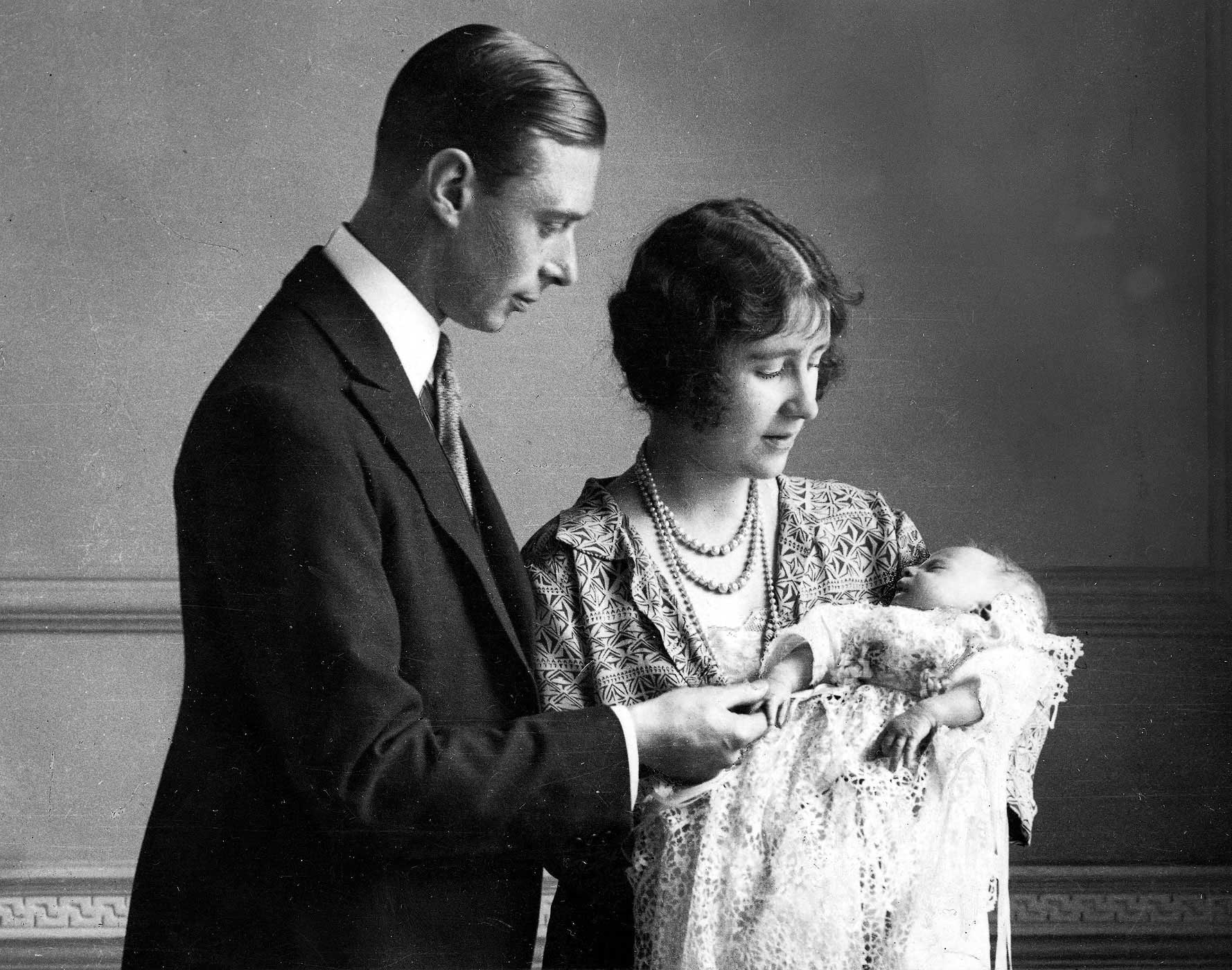 1926. The Duke and Duchess of York (later King George VI and Queen Elizabeth, the Queen Mother) pictured with their daughter (later, Queen Elizabeth II) as she sleeps in a precious christening robe, which has been used in the Royal Family for generations.