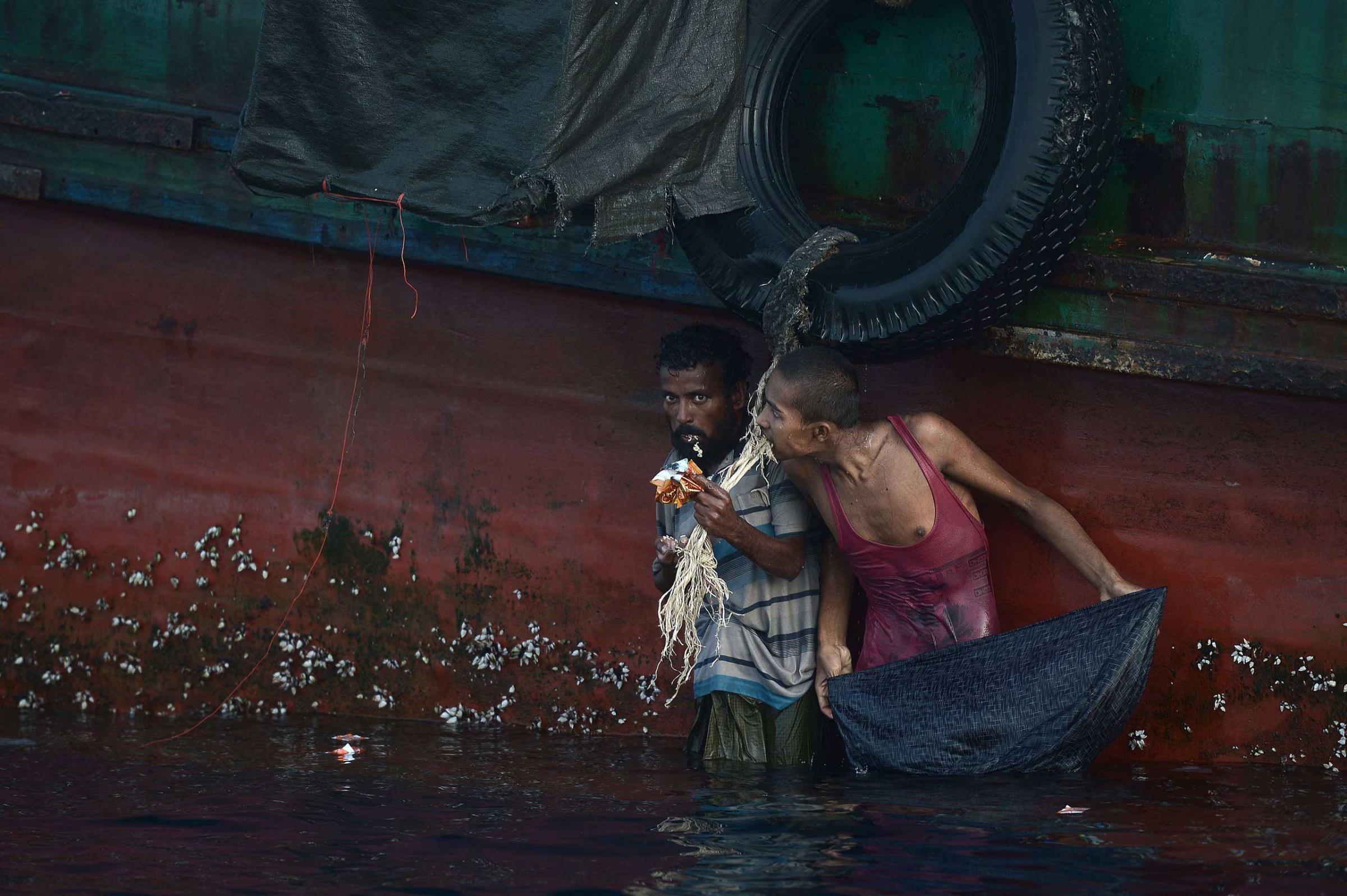 A Rohingya migrant eats food dropped by a Thai army helicopter after he jumped to collect the supplies at sea from a boat drifting in Thai waters off the southern island of Koh Lipe in the Andaman sea on May 14, 2015.