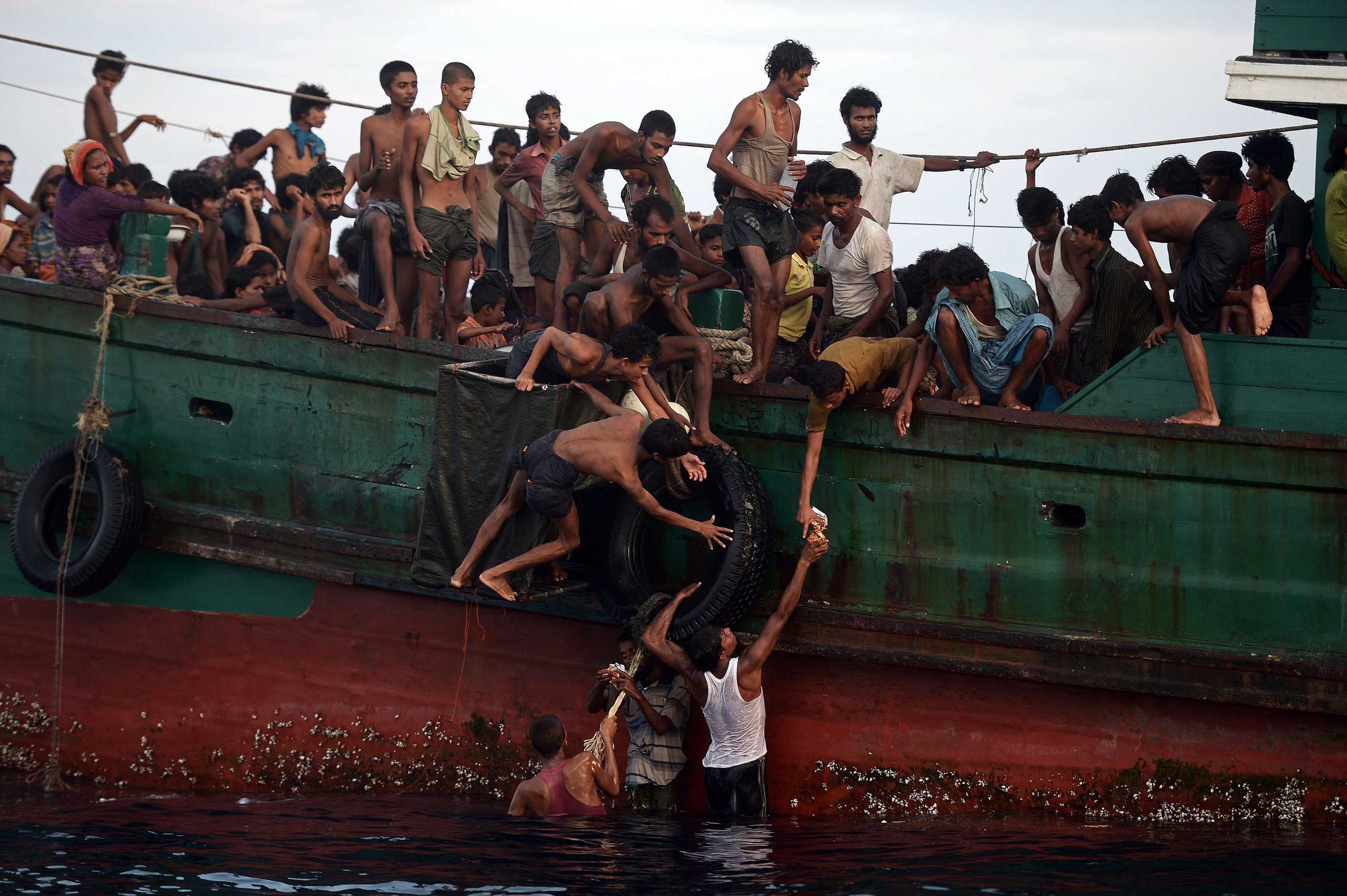 Rohingya migrants pass food supplies dropped by a Thai army helicopter to others aboard a boat drifting in Thai waters off the southern island of Koh Lipe in the Andaman sea on May 14, 2015.