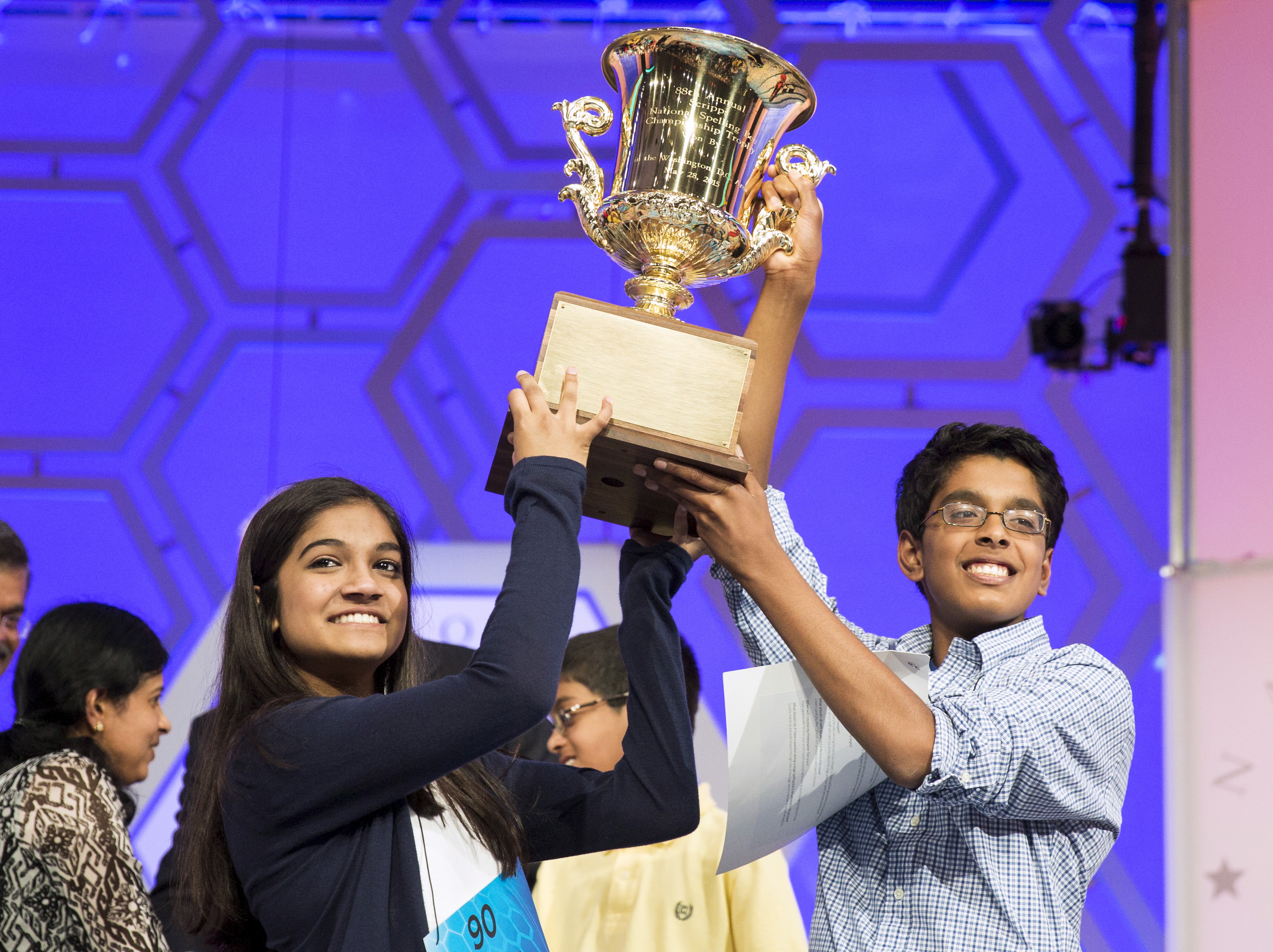Vanya Shivashankar of Olathe, Kansas, and Gokul Venkatachalam, St. Louis Missouri lift the trophy after becoming co-champions after the final round of the 88th annual Scripps National Spelling Bee