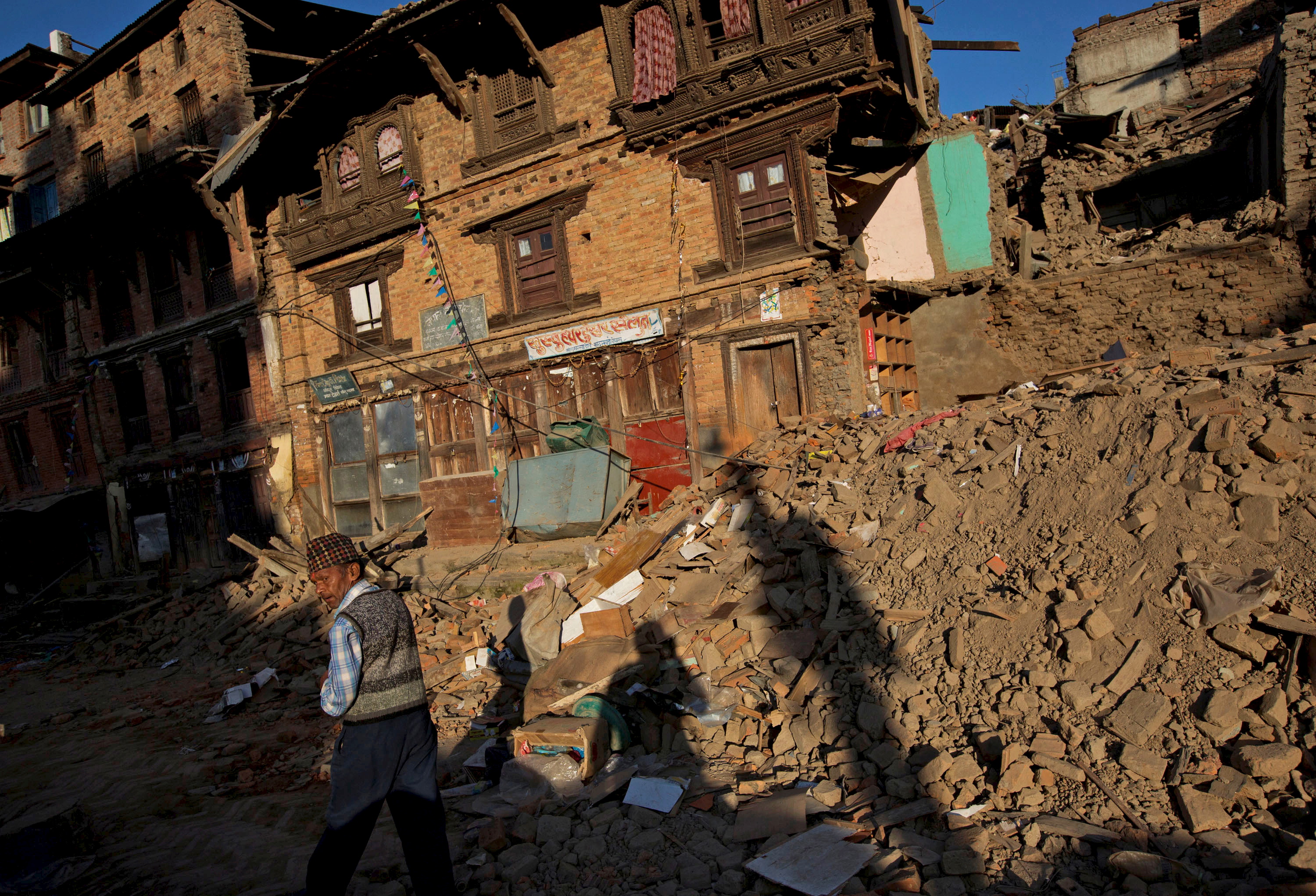 An earthquake victim walks along a street near collapsed houses in Sankhu, on the outskirts of Kathmandu
