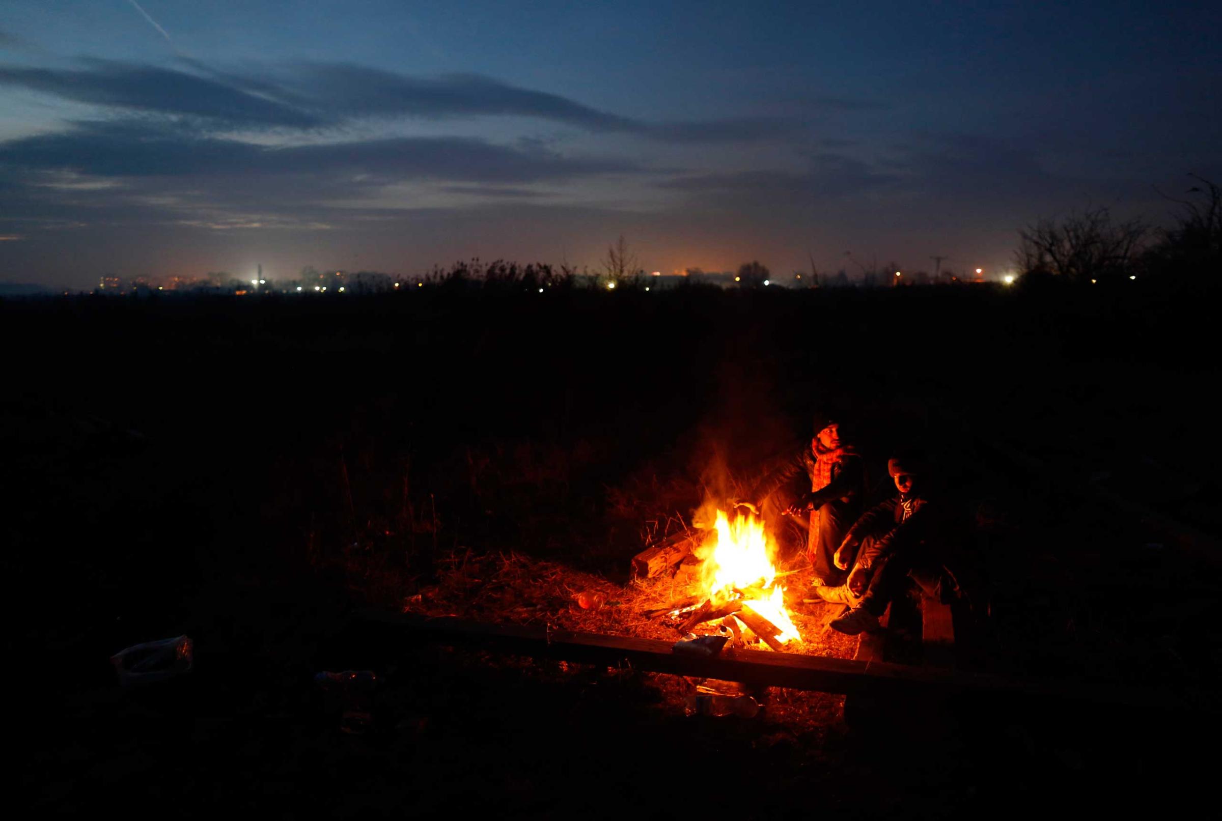Migrants gather around the fire which they use for cooking and for warmth in the abandoned brick factory in the northern Serbian town of Subotica, near the border between Serbia and Hungary, on Dec. 15, 2014.