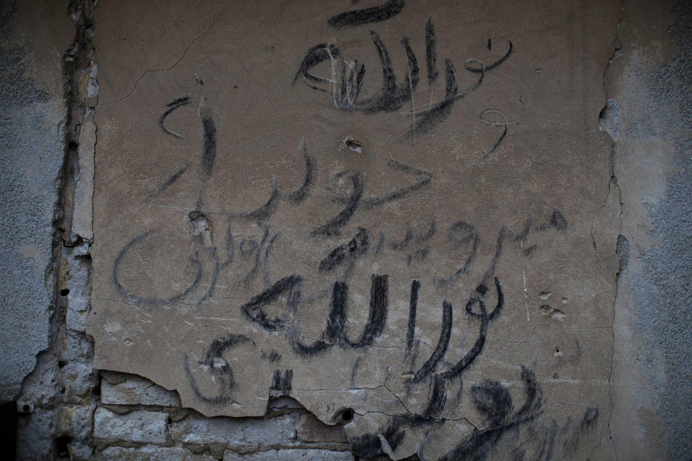 A graffiti in Arabic letters is seen on a wall of an abandoned factory used as a resting point by migrants on the outskirts of Subotica, 90 miles north of Belgrade, Serbia on Feb. 26, 2015.