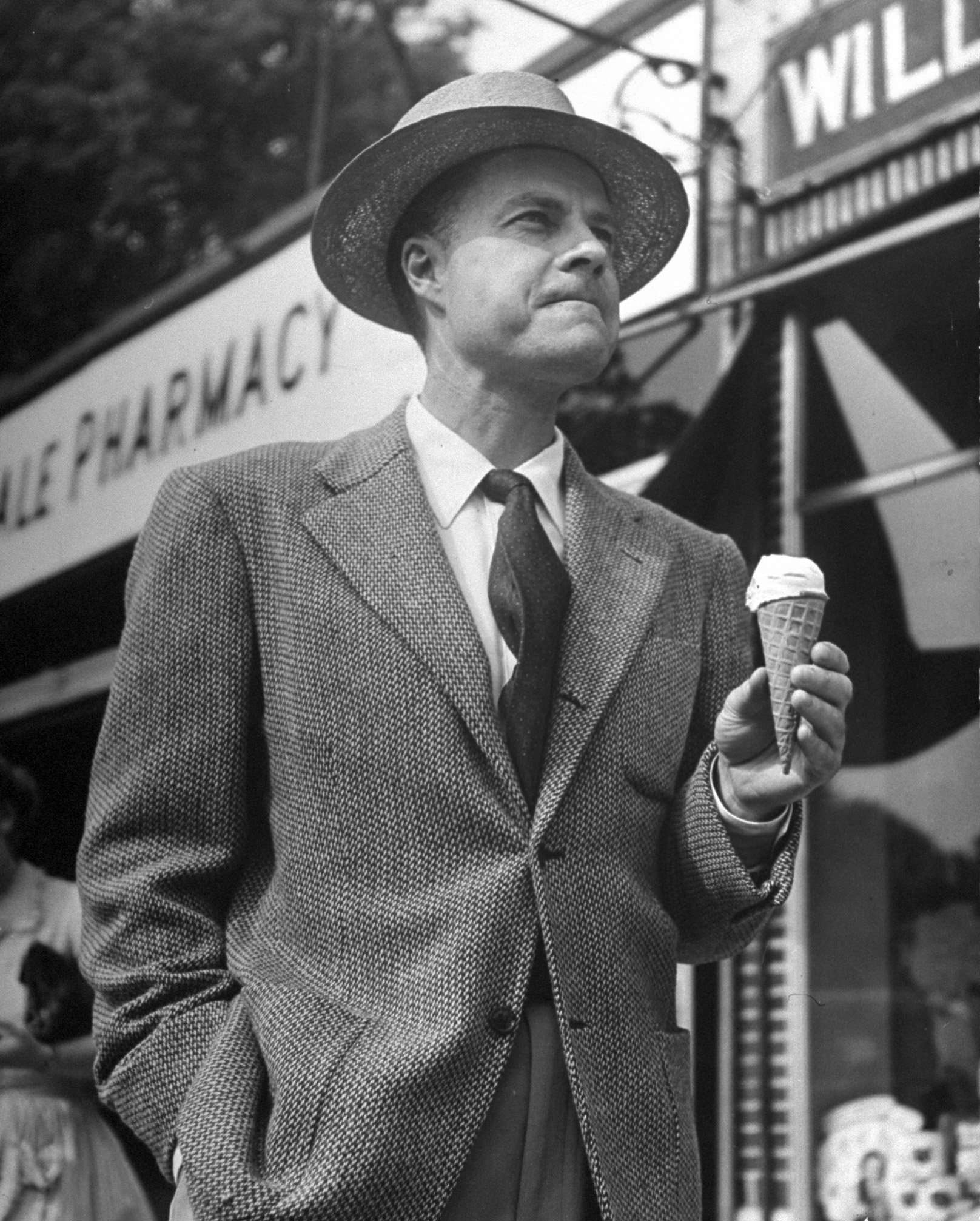 Businessman eating ice cream cone outside a drugstore, 1946.