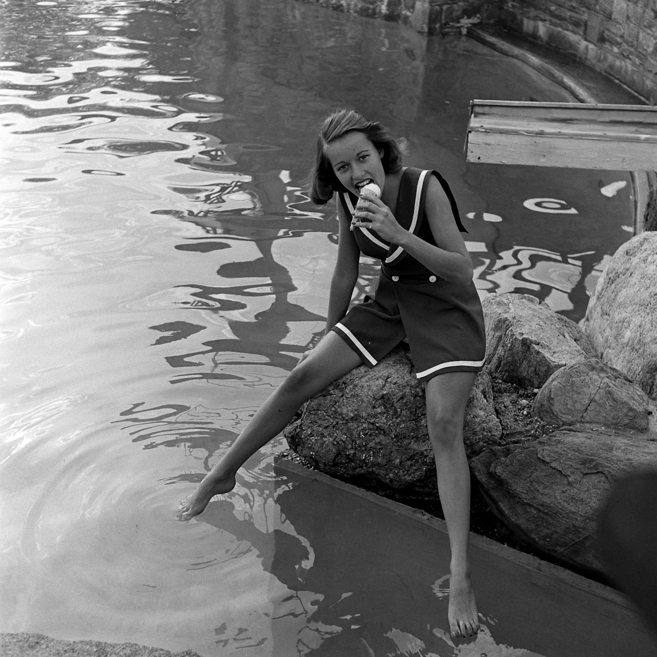 Bathing suit model eating ice cream by a lake, 1946.
