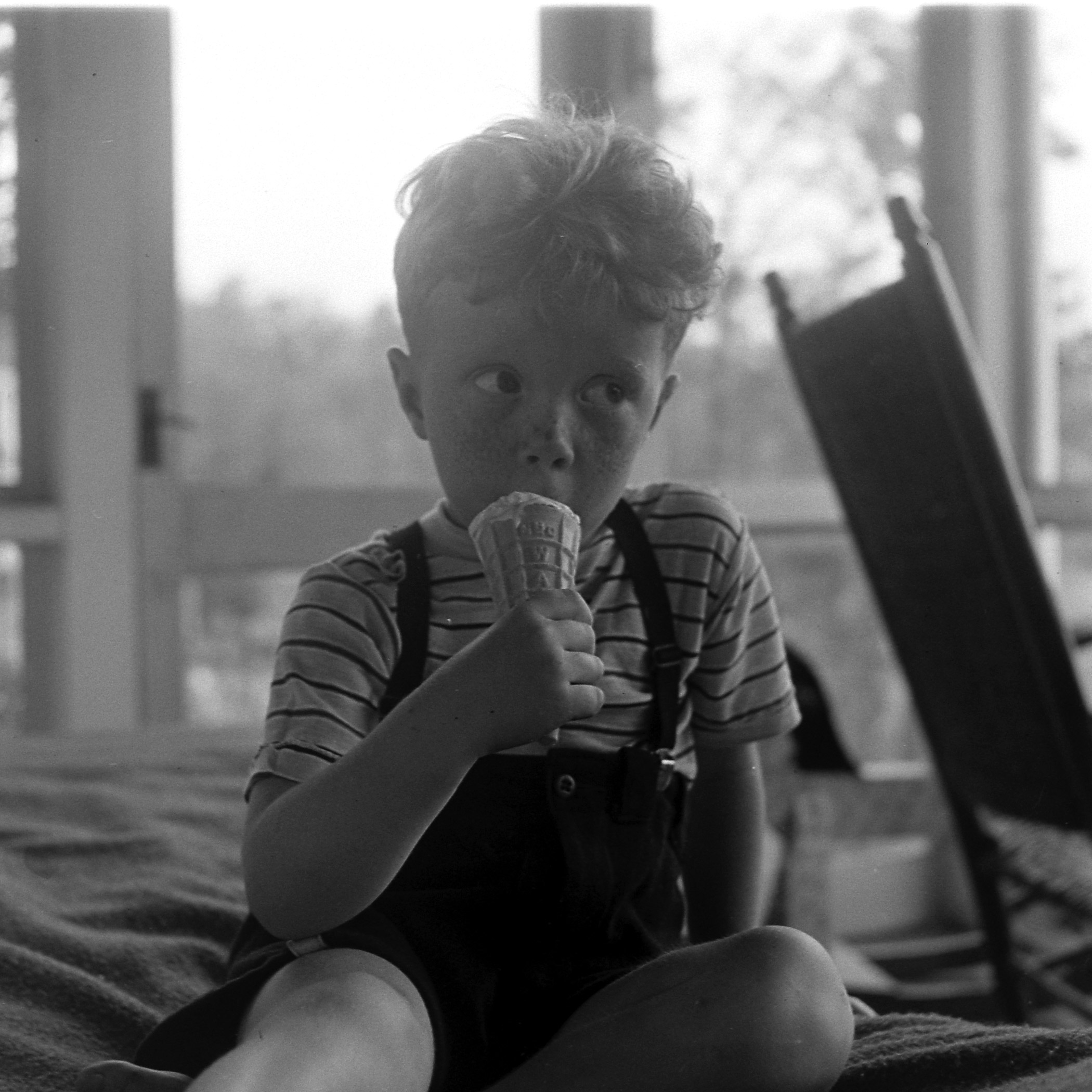 Little boy eating ice cream on the screened-in porch in Cape Cod, 1946.