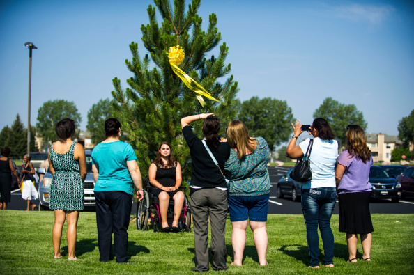 Ashley Moser poses for a picture in front of a tree bearing a ribbon for her 6-year-old daughter Veronica Moser-Sullivan, who was killed in the attack on the Century Aurora 16 movie theater in Aurora, Colo., on July 20, 2014 (Kent Nishimura—Denver Post via Getty Images)