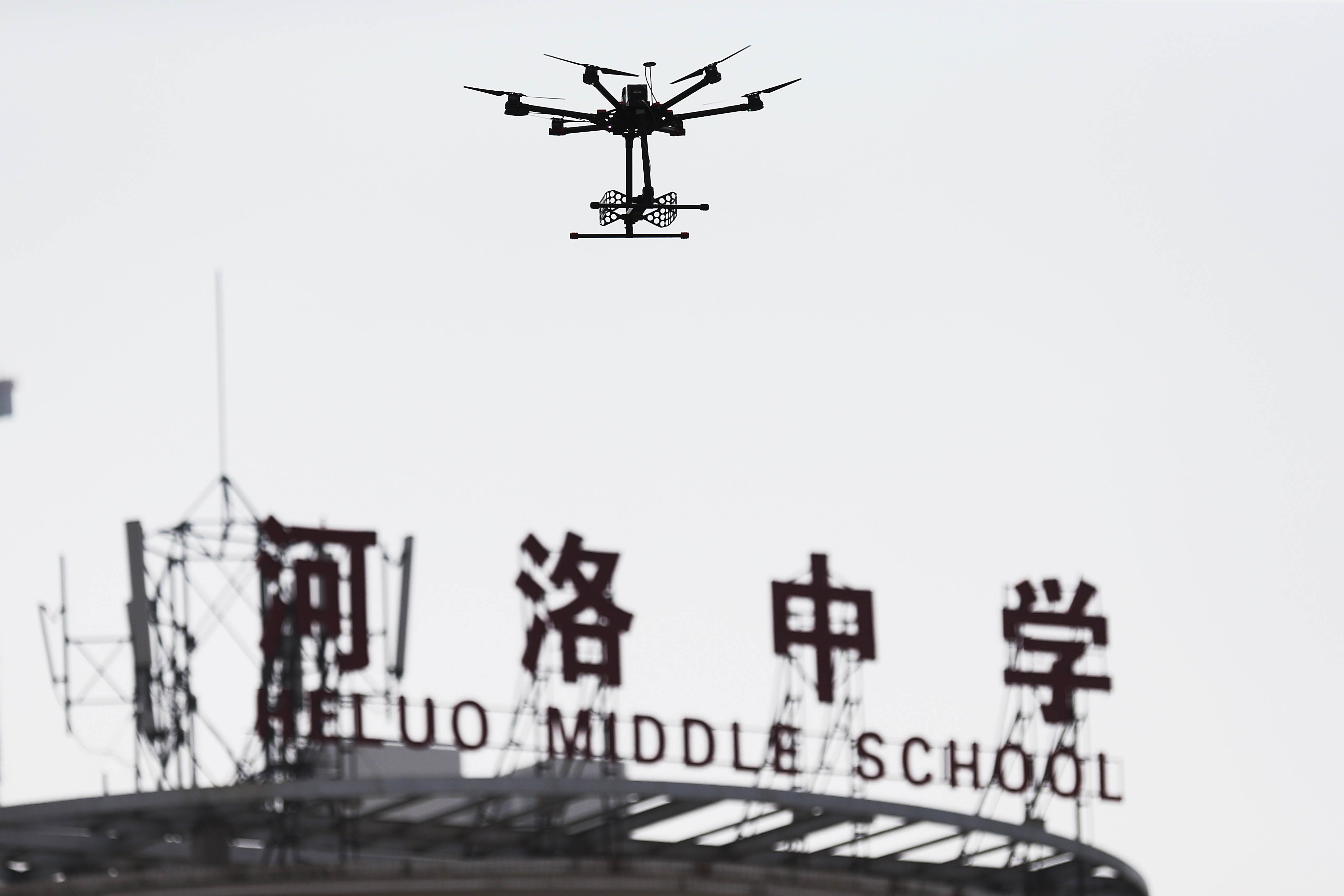 An unmanned aerial vehicle (UAV), or drone, used to detect radio signals to prevent student from cheating, hovers over an exam site during the first examination of the 2015 National College Entrance Exam, also known as Gaokao, at Heluo Middle School in Luoyang city, central China's Henan province, 7 June 2015. (Dong Lifei/Imaginechina)
